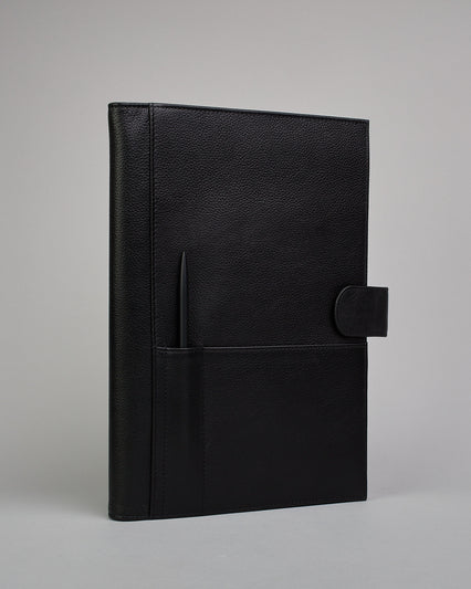 Schwarzer Leder Notizbucheinband mit leichter Narbund. Der Einband hat außen ein flaches Fach in das ein Stift und das Handy gesteckt werden können. Das Notizbuch lässt sich seitlich mit einer Lasche und einem darunterliegenden Druckknopf verschließen. Innen bietet das Notizbuch rechts Platz um ein Buch einzustecken und links gibt es viele Fächer für weitere Notizzettel, Visitkarten und mehr. #1