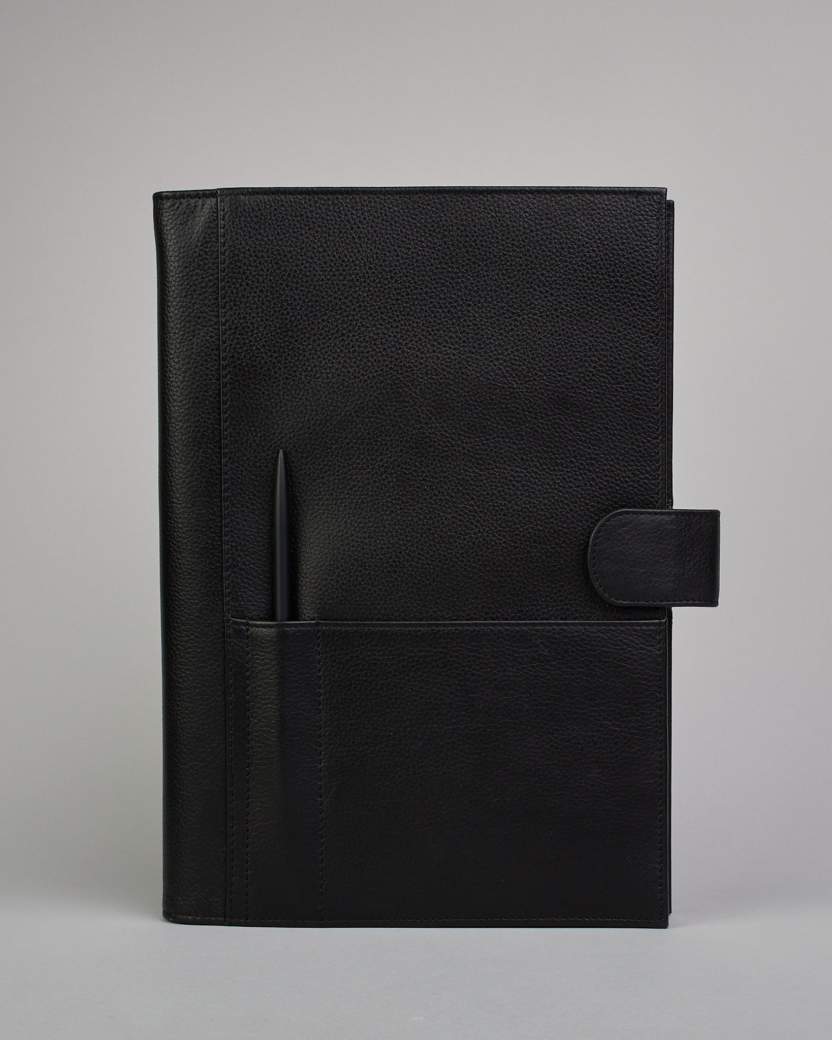 Schwarzer Leder Notizbucheinband mit leichter Narbund. Der Einband hat außen ein flaches Fach in das ein Stift und das Handy gesteckt werden können. Das Notizbuch lässt sich seitlich mit einer Lasche und einem darunterliegenden Druckknopf verschließen. Innen bietet das Notizbuch rechts Platz um ein Buch einzustecken und links gibt es viele Fächer für weitere Notizzettel, Visitkarten und mehr. #2