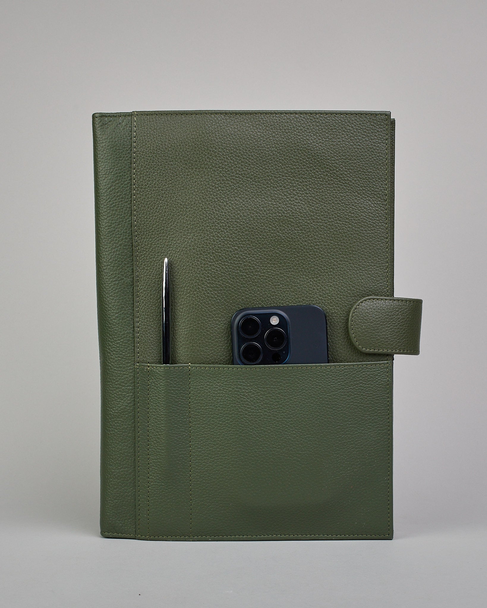 Dunkelgrüner Leder Notizbucheinband mit leichter Narbund. Der Einband hat außen ein flaches Fach in das ein Stift und das Handy gesteckt werden können. Das Notizbuch lässt sich seitlich mit einer Lasche und einem darunterliegenden Druckknopf verschließen. Innen bietet das Notizbuch rechts Platz um ein Buch einzustecken und links gibt es viele Fächer für weitere Notizzettel, Visitkarten und mehr. #4