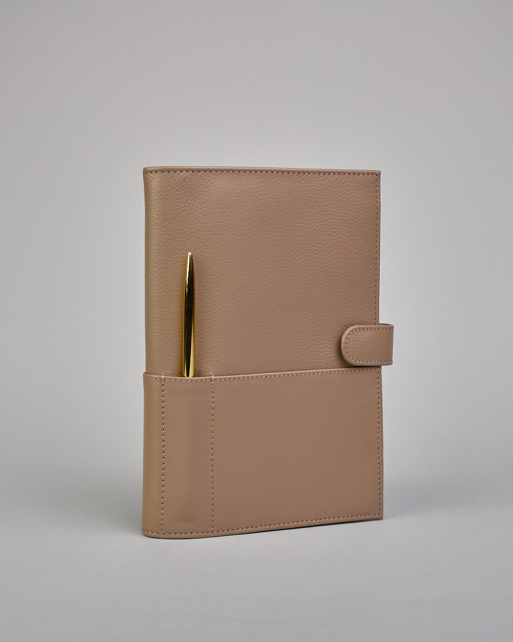 Beiger Leder Notizbucheinband mit leichter Narbund. Der Einband hat außen ein flaches Fach in das ein Stift und das Handy gesteckt werden können. Das Notizbuch lässt sich seitlich mit einer Lasche und einem darunterliegenden Druckknopf verschließen. Innen bietet das Notizbuch rechts Platz um ein Buch einzustecken und links gibt es viele Fächer für weitere Notizzettel, Visitkarten und mehr. #1