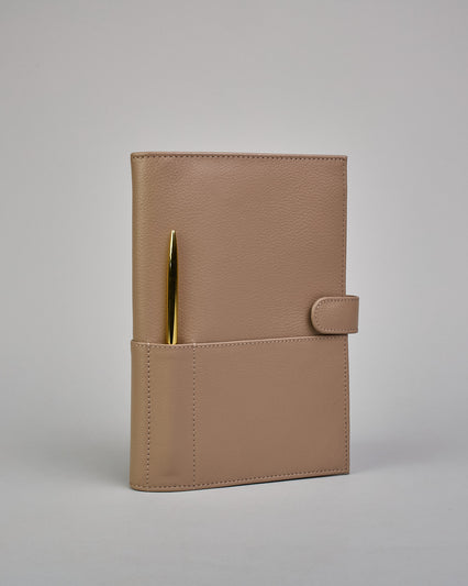 Beiger Leder Notizbucheinband mit leichter Narbund. Der Einband hat außen ein flaches Fach in das ein Stift und das Handy gesteckt werden können. Das Notizbuch lässt sich seitlich mit einer Lasche und einem darunterliegenden Druckknopf verschließen. Innen bietet das Notizbuch rechts Platz um ein Buch einzustecken und links gibt es viele Fächer für weitere Notizzettel, Visitkarten und mehr. #1