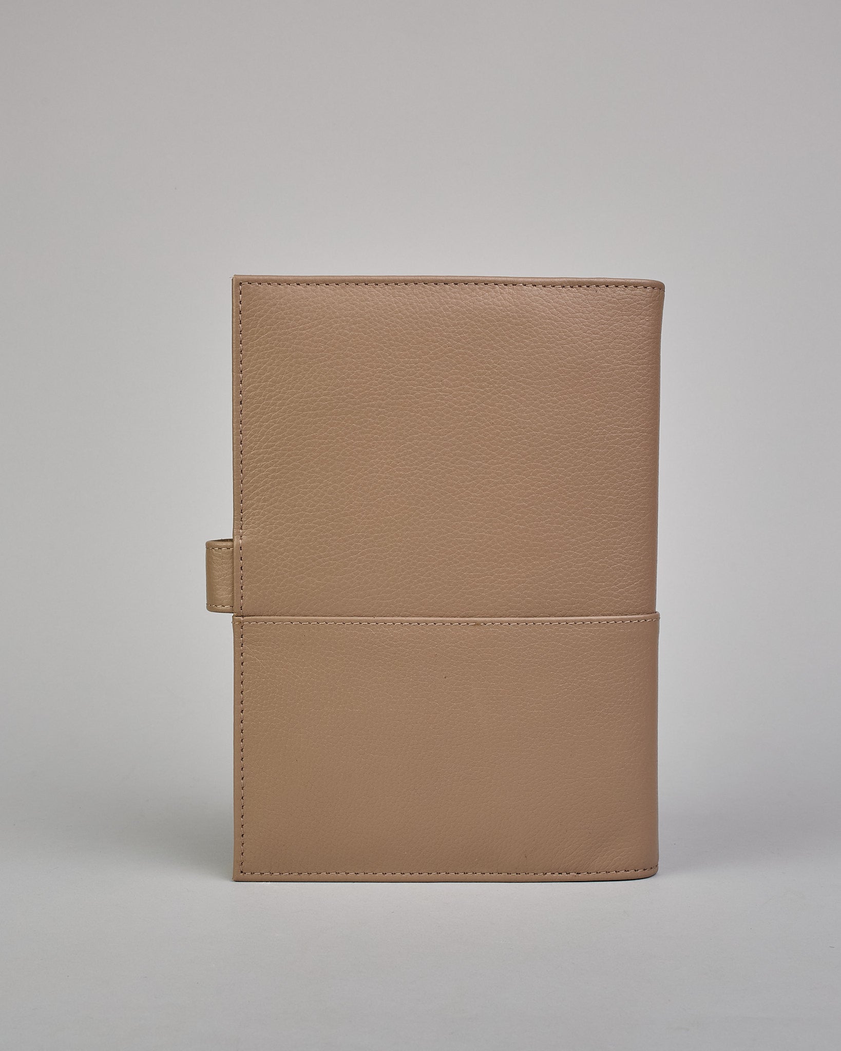 Beiger Leder Notizbucheinband mit leichter Narbund. Der Einband hat außen ein flaches Fach in das ein Stift und das Handy gesteckt werden können. Das Notizbuch lässt sich seitlich mit einer Lasche und einem darunterliegenden Druckknopf verschließen. Innen bietet das Notizbuch rechts Platz um ein Buch einzustecken und links gibt es viele Fächer für weitere Notizzettel, Visitkarten und mehr. #3