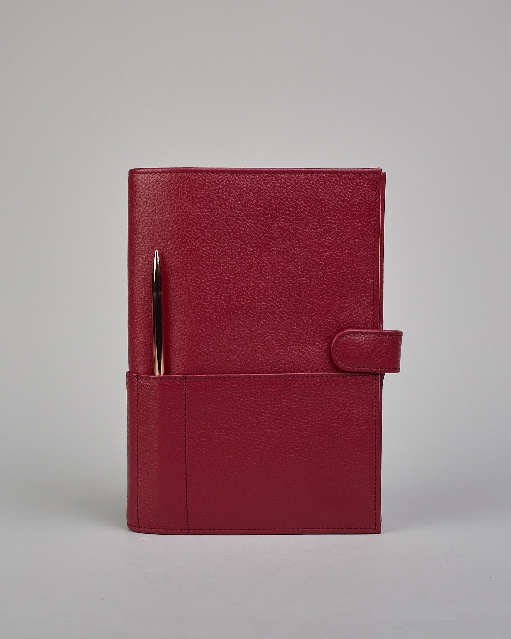 Bordeauxroter Leder Notizbucheinband mit leichter Narbund. Der Einband hat außen ein flaches Fach in das ein Stift und das Handy gesteckt werden können. Das Notizbuch lässt sich seitlich mit einer Lasche und einem darunterliegenden Druckknopf verschließen. Innen bietet das Notizbuch rechts Platz um ein Buch einzustecken und links gibt es viele Fächer für weitere Notizzettel, Visitkarten und mehr. #2