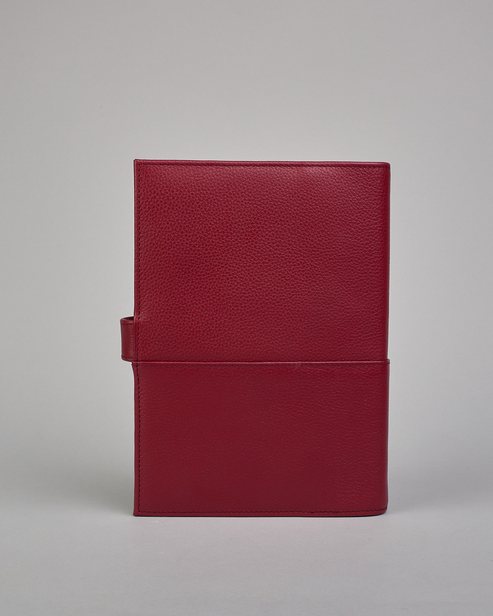 Bordeauxroter Leder Notizbucheinband mit leichter Narbund. Der Einband hat außen ein flaches Fach in das ein Stift und das Handy gesteckt werden können. Das Notizbuch lässt sich seitlich mit einer Lasche und einem darunterliegenden Druckknopf verschließen. Innen bietet das Notizbuch rechts Platz um ein Buch einzustecken und links gibt es viele Fächer für weitere Notizzettel, Visitkarten und mehr. #3