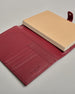 Bordeauxroter Leder Notizbucheinband mit leichter Narbund. Der Einband hat außen ein flaches Fach in das ein Stift und das Handy gesteckt werden können. Das Notizbuch lässt sich seitlich mit einer Lasche und einem darunterliegenden Druckknopf verschließen. Innen bietet das Notizbuch rechts Platz um ein Buch einzustecken und links gibt es viele Fächer für weitere Notizzettel, Visitkarten und mehr. #7