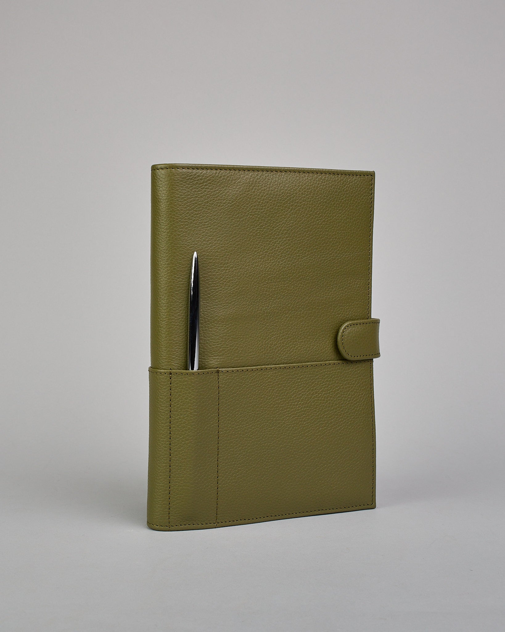 Grüner Leder Notizbucheinband mit leichter Narbund. Der Einband hat außen ein flaches Fach in das ein Stift und das Handy gesteckt werden können. Das Notizbuch lässt sich seitlich mit einer Lasche und einem darunterliegenden Druckknopf verschließen. Innen bietet das Notizbuch rechts Platz um ein Buch einzustecken und links gibt es viele Fächer für weitere Notizzettel, Visitkarten und mehr. #1