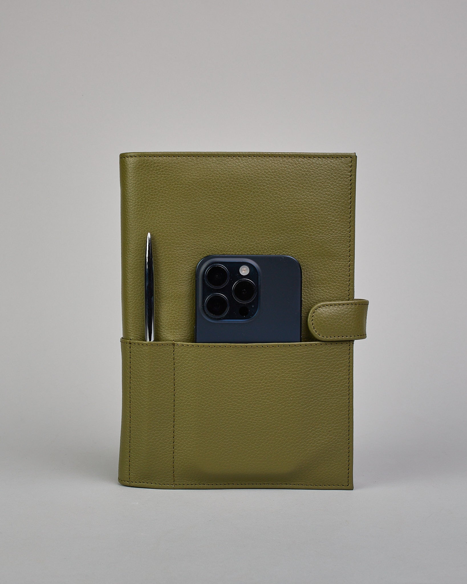 Grüner Leder Notizbucheinband mit leichter Narbund. Der Einband hat außen ein flaches Fach in das ein Stift und das Handy gesteckt werden können. Das Notizbuch lässt sich seitlich mit einer Lasche und einem darunterliegenden Druckknopf verschließen. Innen bietet das Notizbuch rechts Platz um ein Buch einzustecken und links gibt es viele Fächer für weitere Notizzettel, Visitkarten und mehr. #4