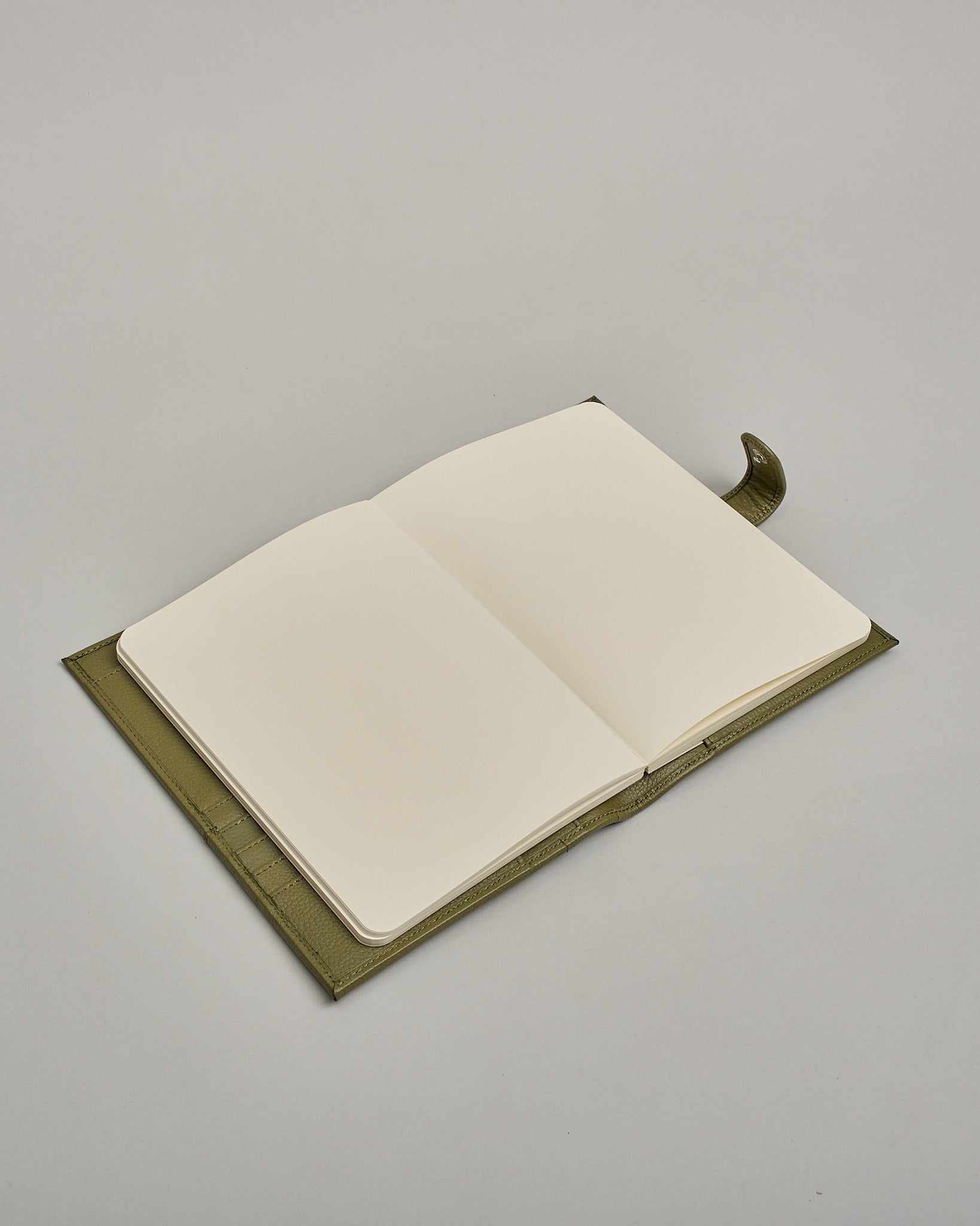 Grüner Leder Notizbucheinband mit leichter Narbund. Der Einband hat außen ein flaches Fach in das ein Stift und das Handy gesteckt werden können. Das Notizbuch lässt sich seitlich mit einer Lasche und einem darunterliegenden Druckknopf verschließen. Innen bietet das Notizbuch rechts Platz um ein Buch einzustecken und links gibt es viele Fächer für weitere Notizzettel, Visitkarten und mehr. #8