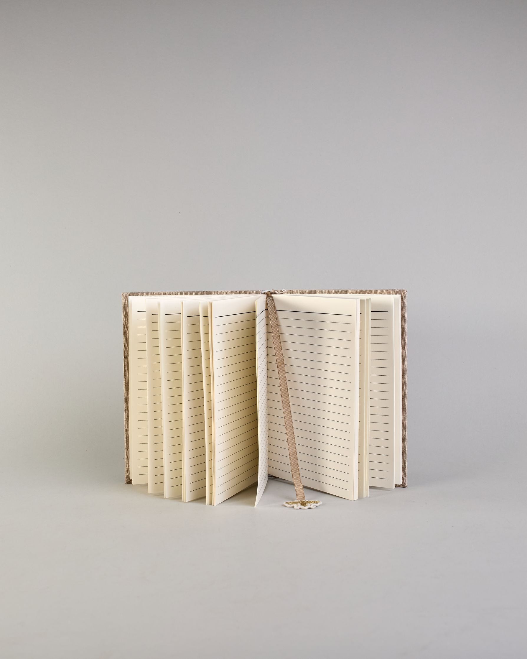 Beiges Notizbuch mti Baumwolleinband und vielen gestickten goldenen Bienen in regelmäßigen Abständen auf dem Einband. Lesezeichen mit goldener Biene als Anhänger. Linierte Seiten innen. #5