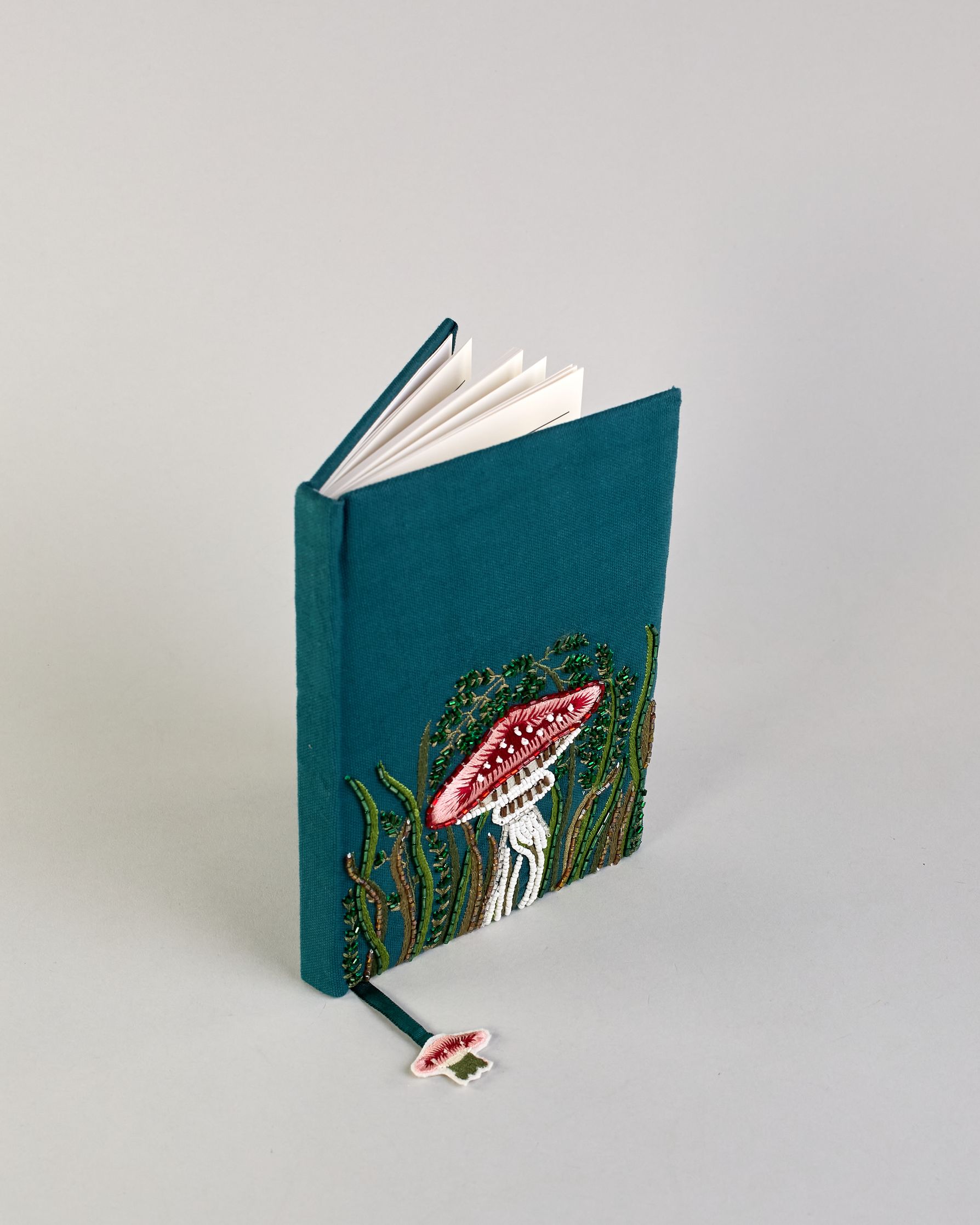 Petrolfarbenes Notizbuch mit Baumwolleinband und großem Fliegenpilz aus Perlen gestickt auf den Bucheinband, runderherum ist noch Gras aus Perlen. Lesezeichen mit Fliegenpilz als Anähnger. Linierte Seiten #3