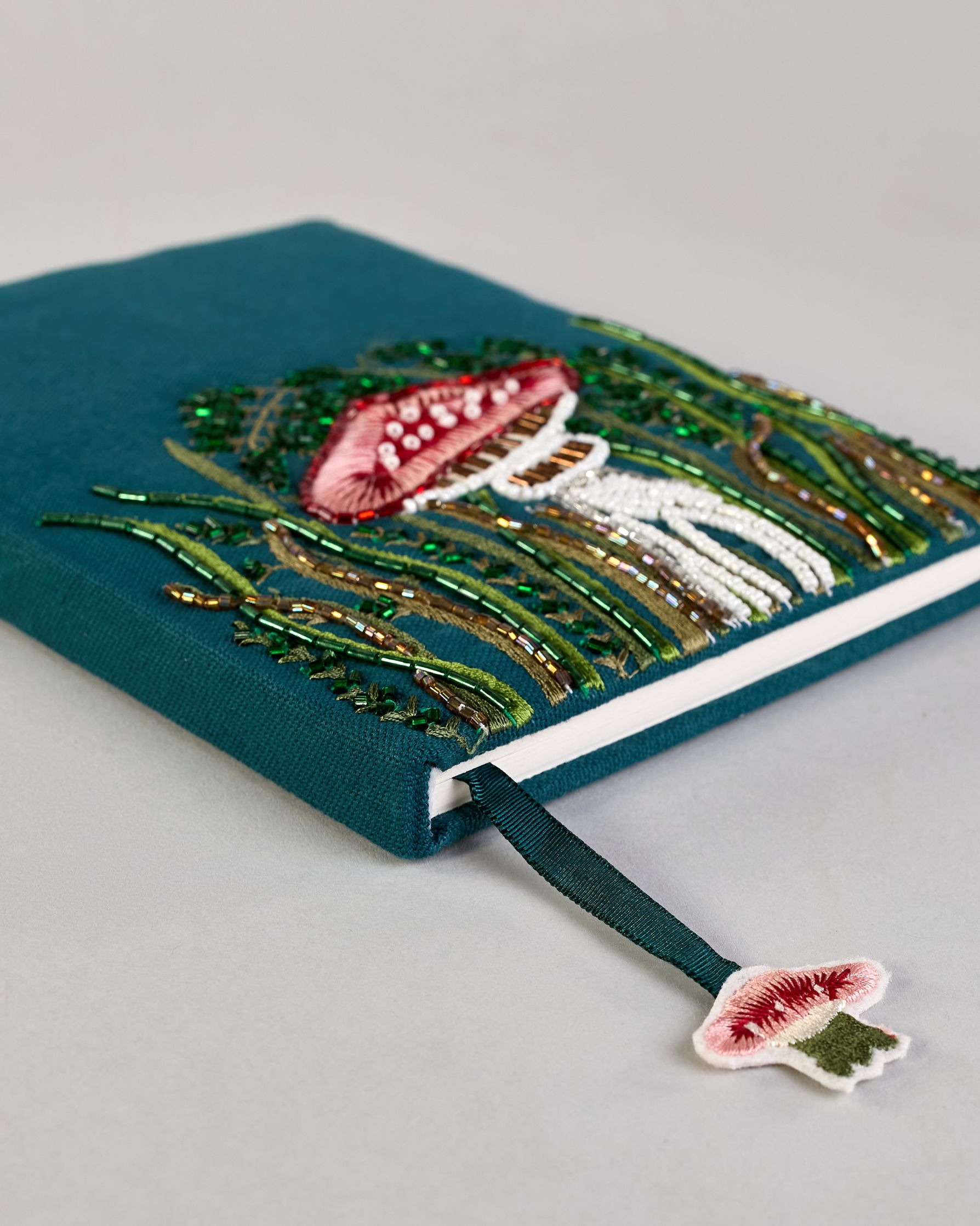 Petrolfarbenes Notizbuch mit Baumwolleinband und großem Fliegenpilz aus Perlen gestickt auf den Bucheinband, runderherum ist noch Gras aus Perlen. Lesezeichen mit Fliegenpilz als Anähnger. Linierte Seiten #4