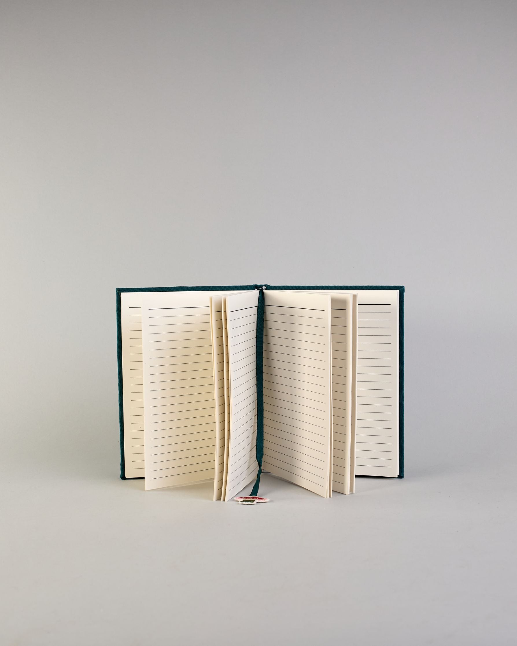 Petrolfarbenes Notizbuch mit Baumwolleinband und großem Fliegenpilz aus Perlen gestickt auf den Bucheinband, runderherum ist noch Gras aus Perlen. Lesezeichen mit Fliegenpilz als Anähnger. Linierte Seiten #6