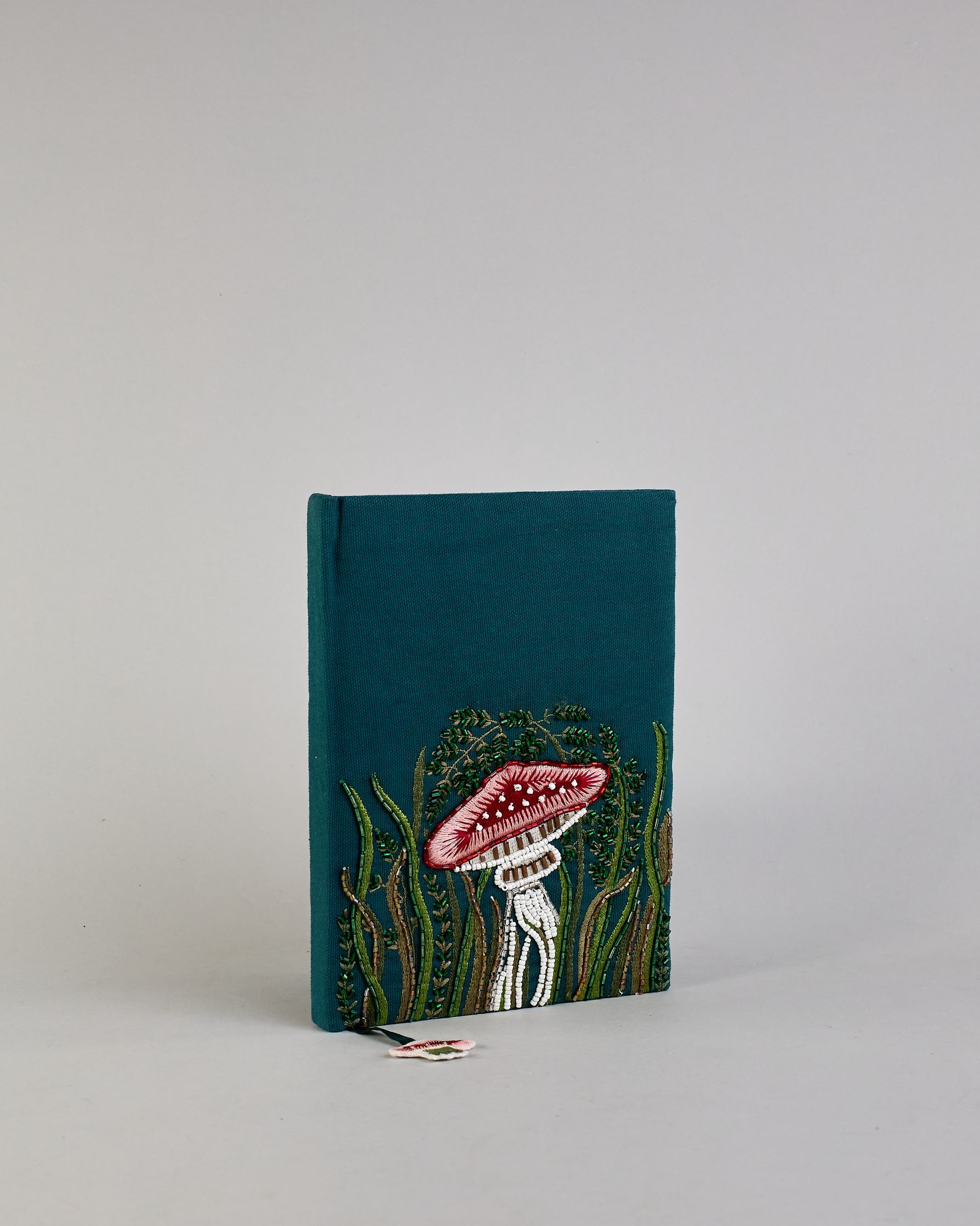 Petrolfarbenes Notizbuch mit Baumwolleinband und großem Fliegenpilz aus Perlen gestickt auf den Bucheinband, runderherum ist noch Gras aus Perlen. Lesezeichen mit Fliegenpilz als Anähnger. Linierte Seiten #7