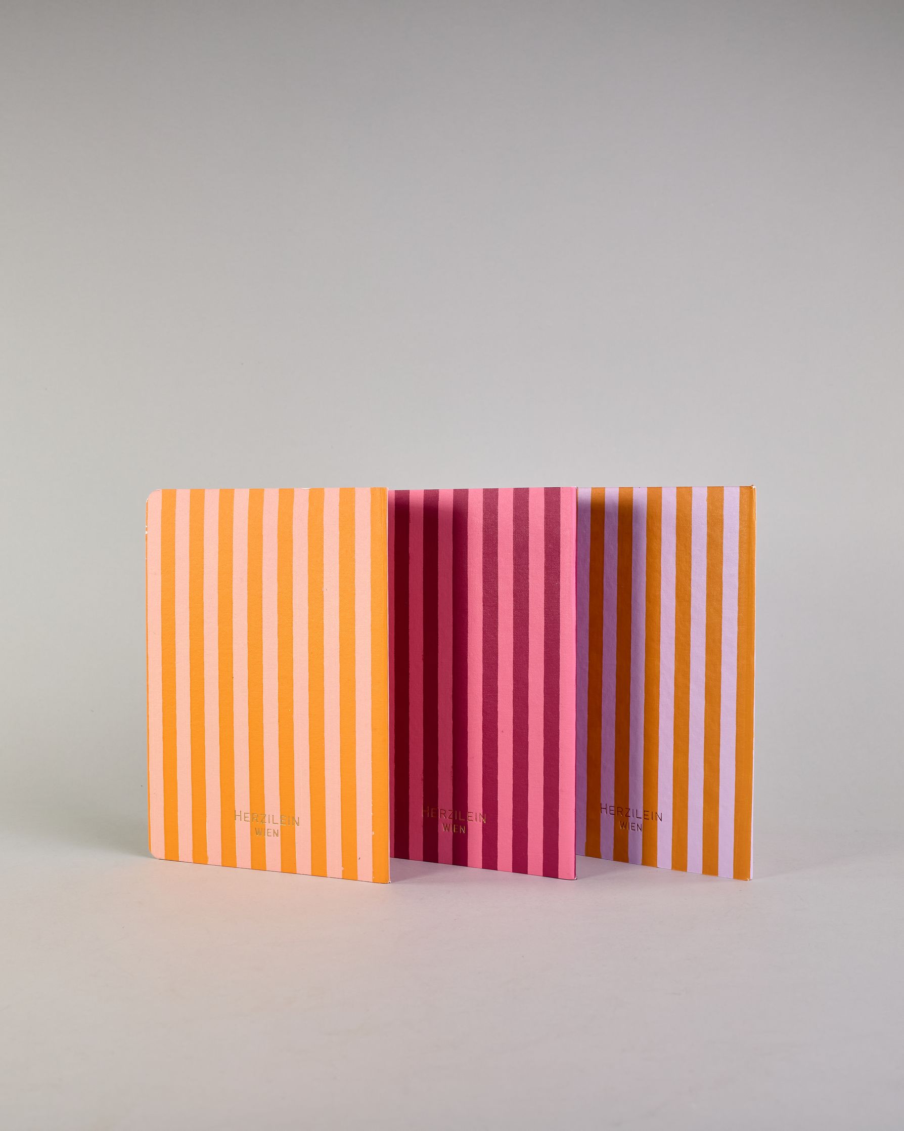 Set aus drei A5-Heften mit recyceltem Baumwolleinband. Die Hefte sind mit senkrechten Streifen in Blau- und Grüntönen gestaltet und zeigen auf dem Cover jeweils ein goldener Spruch: Dreams, Thoughts und Ideas. 30 linierte Seiten innen. #3