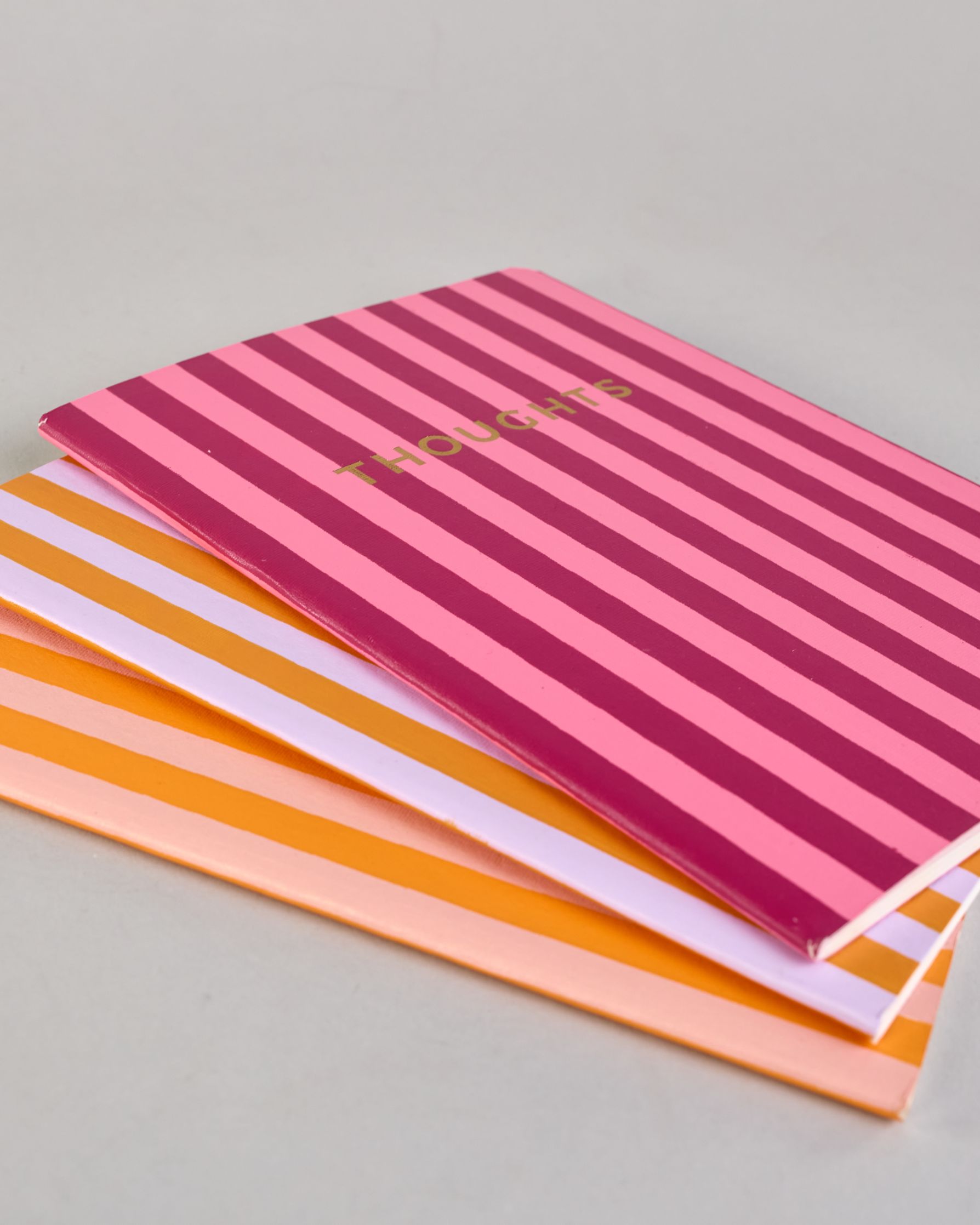 Set aus drei A5-Heften mit recyceltem Baumwolleinband. Die Hefte sind mit senkrechten Streifen in Blau- und Grüntönen gestaltet und zeigen auf dem Cover jeweils ein goldener Spruch: Dreams, Thoughts und Ideas. 30 linierte Seiten innen. #10