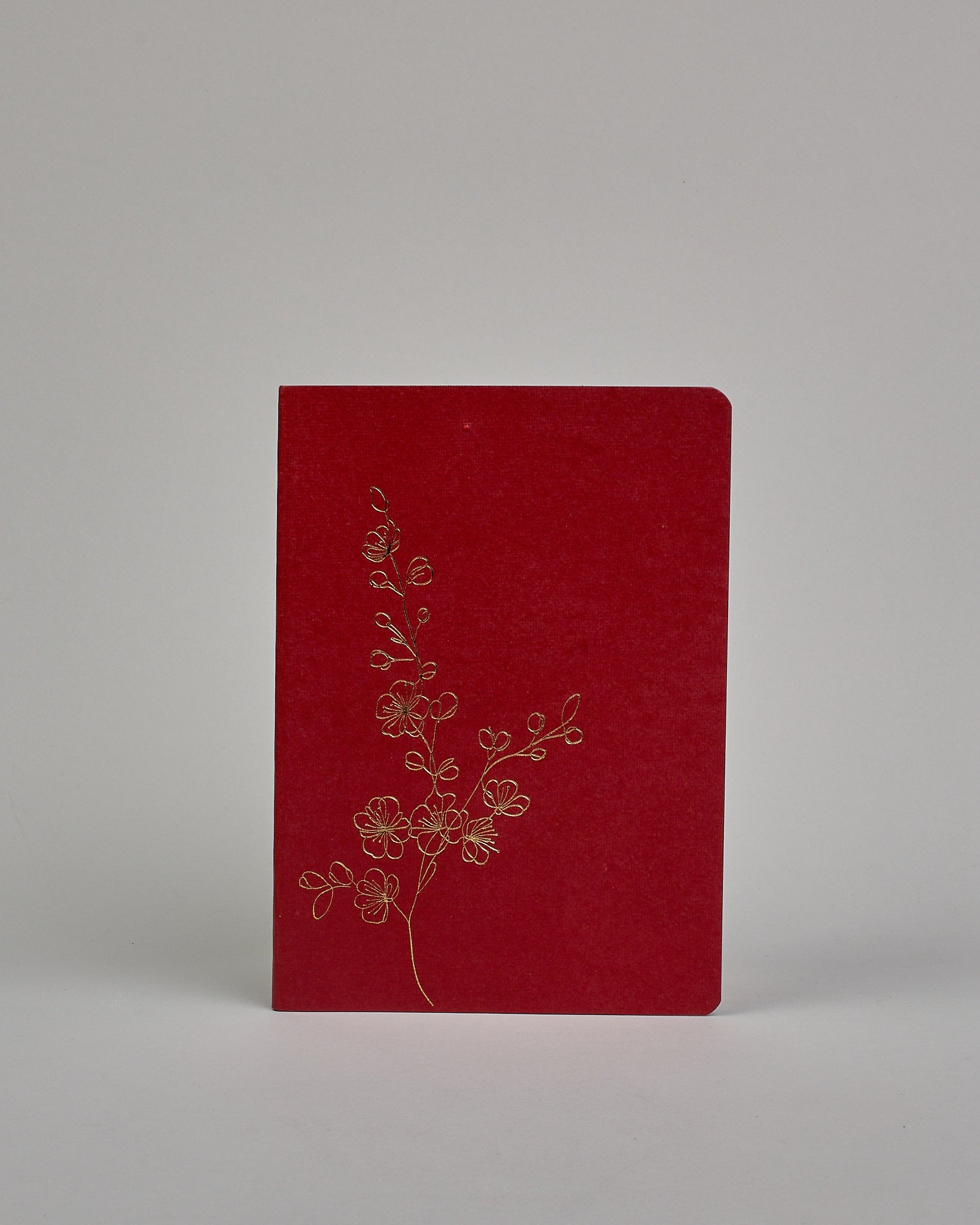Set bestehend aus drei Heften in magenta, dunkelrot und orange. Jedes hat eine andere Prägung oben Mittig in gold. Das magentafarbene eine Pfingstrose, das dunkelrote einen Zweig mit Blumen, das orangene ein vollflächiges Blumenmuster. Innen sind sie glatt. #3