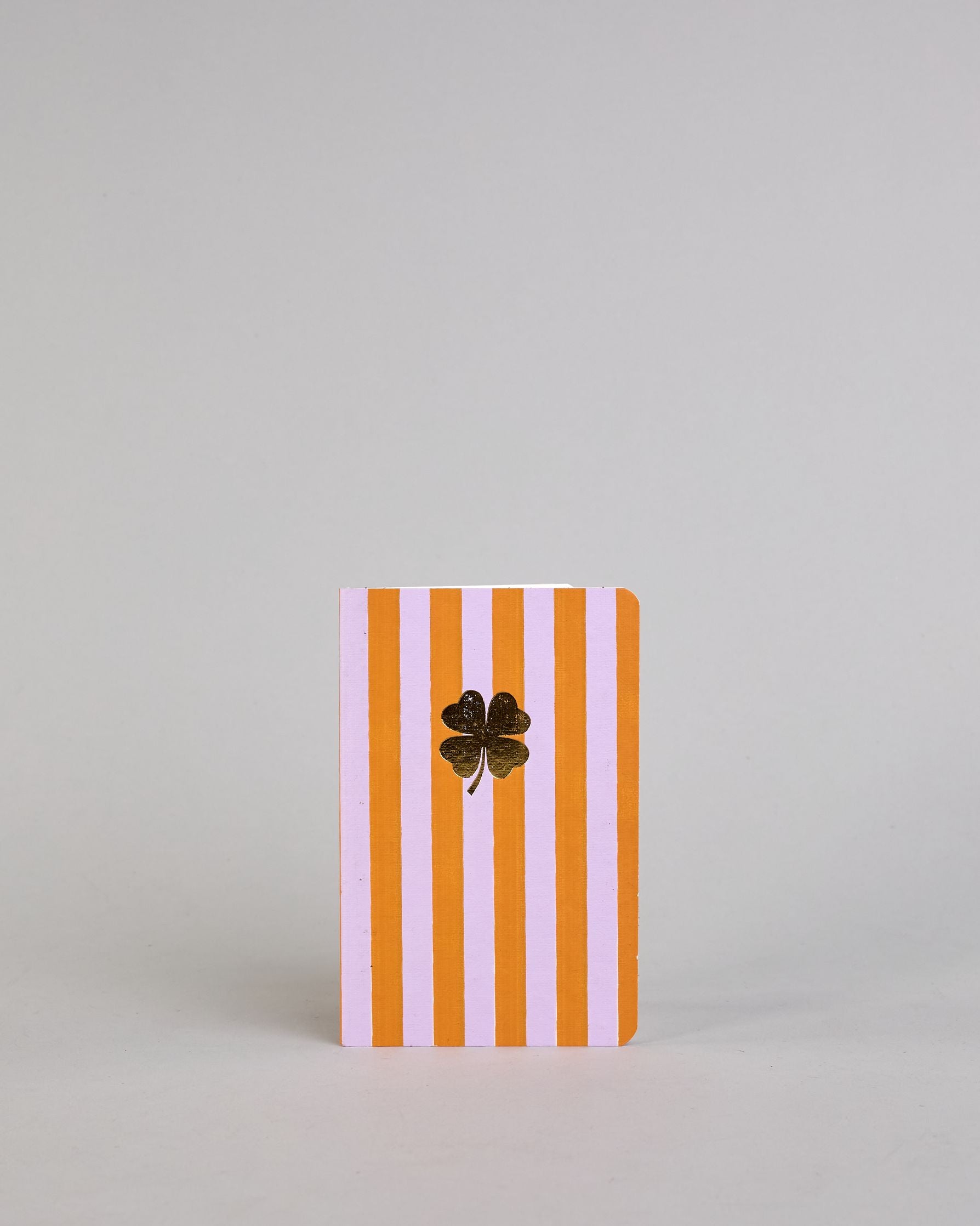 Set aus drei A6-Heften mit recyceltem Baumwolleinband. Die Hefte sind mit senkrechten Streifen in Blau- und Grüntönen gestaltet und zeigen auf dem Cover jeweils ein goldenes Motiv: ein Herz, ein Kleeblatt und eine Libelle. 30 glatte Seiten innen. #7