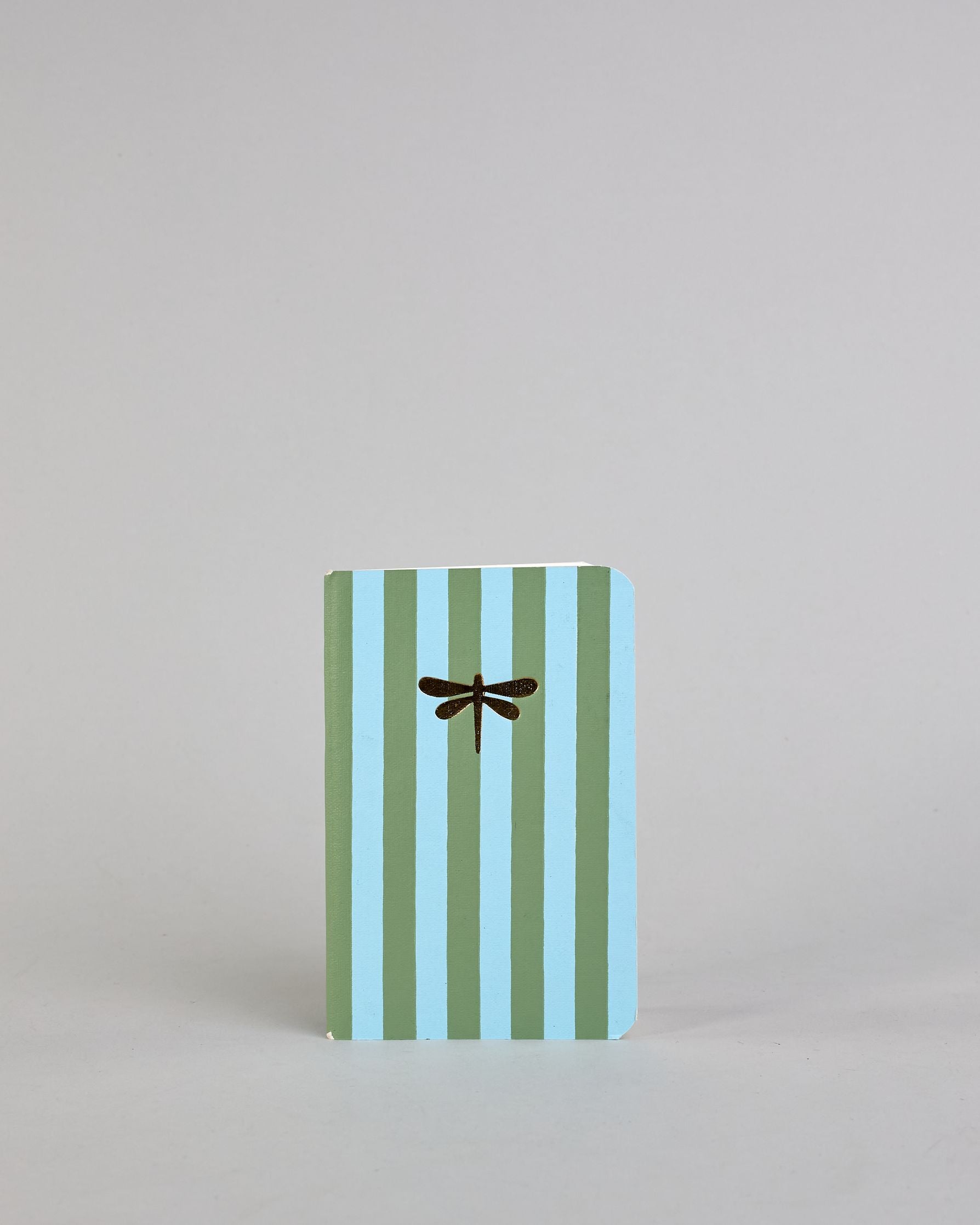 Set aus drei A6-Heften mit recyceltem Baumwolleinband. Die Hefte sind mit senkrechten Streifen in Blau- und Grüntönen gestaltet und zeigen auf dem Cover jeweils ein goldenes Motiv: ein Herz, ein Kleeblatt und eine Libelle. 30 glatte Seiten innen. #5
