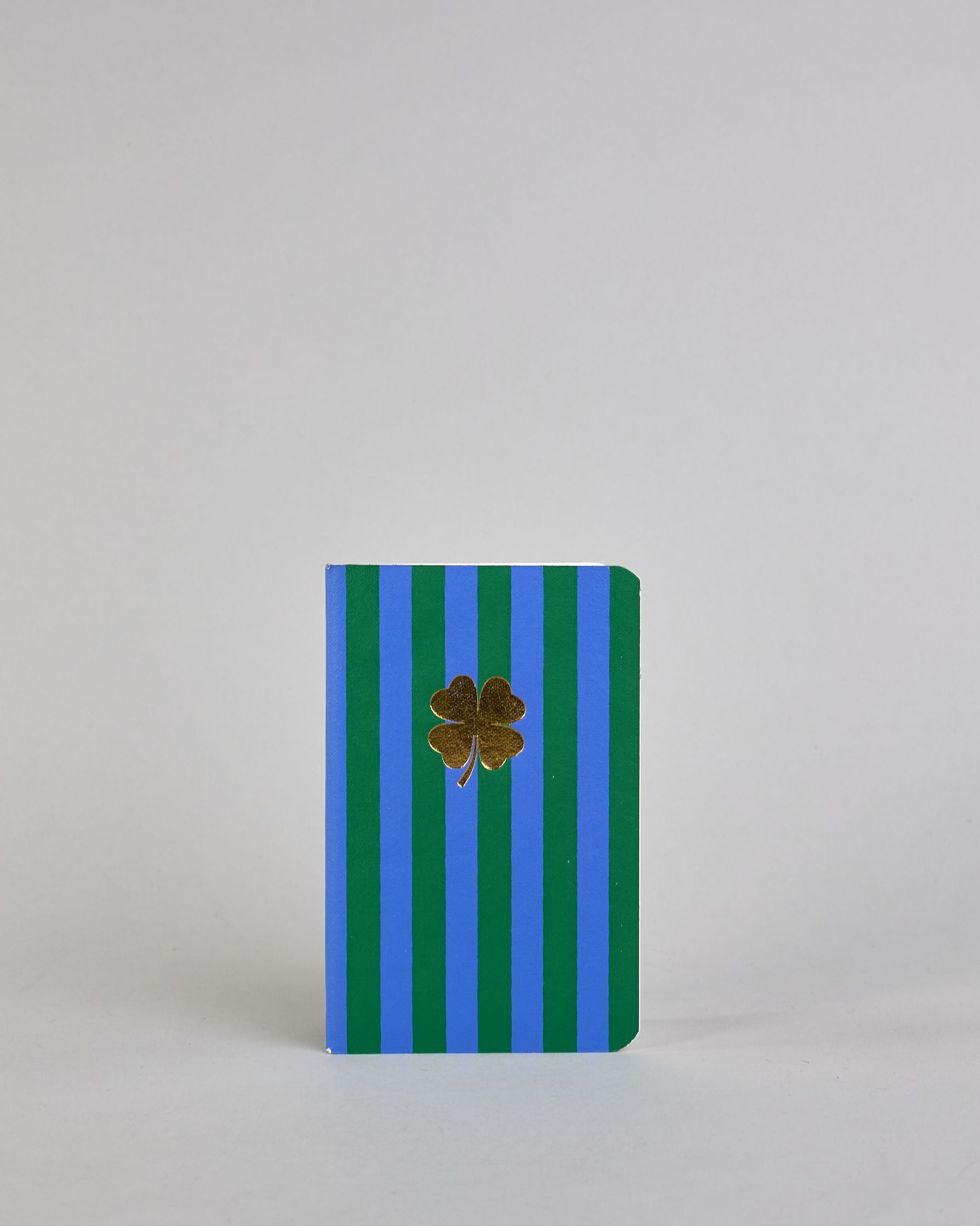 Set aus drei A6-Heften mit recyceltem Baumwolleinband. Die Hefte sind mit senkrechten Streifen in Blau- und Grüntönen gestaltet und zeigen auf dem Cover jeweils ein goldenes Motiv: ein Herz, ein Kleeblatt und eine Libelle. 30 glatte Seiten innen. #6