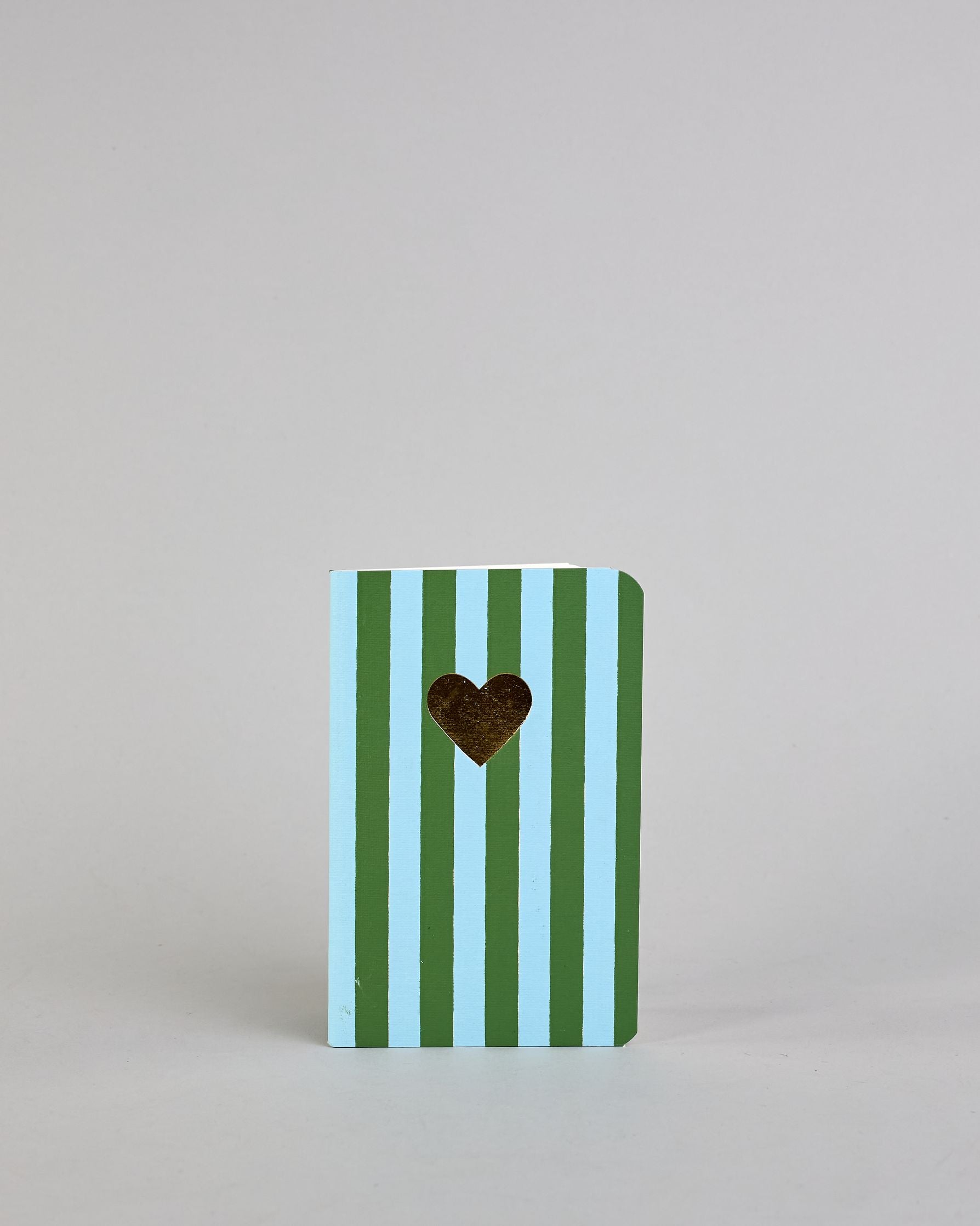 Set aus drei A6-Heften mit recyceltem Baumwolleinband. Die Hefte sind mit senkrechten Streifen in Blau- und Grüntönen gestaltet und zeigen auf dem Cover jeweils ein goldenes Motiv: ein Herz, ein Kleeblatt und eine Libelle. 30 glatte Seiten innen. #7