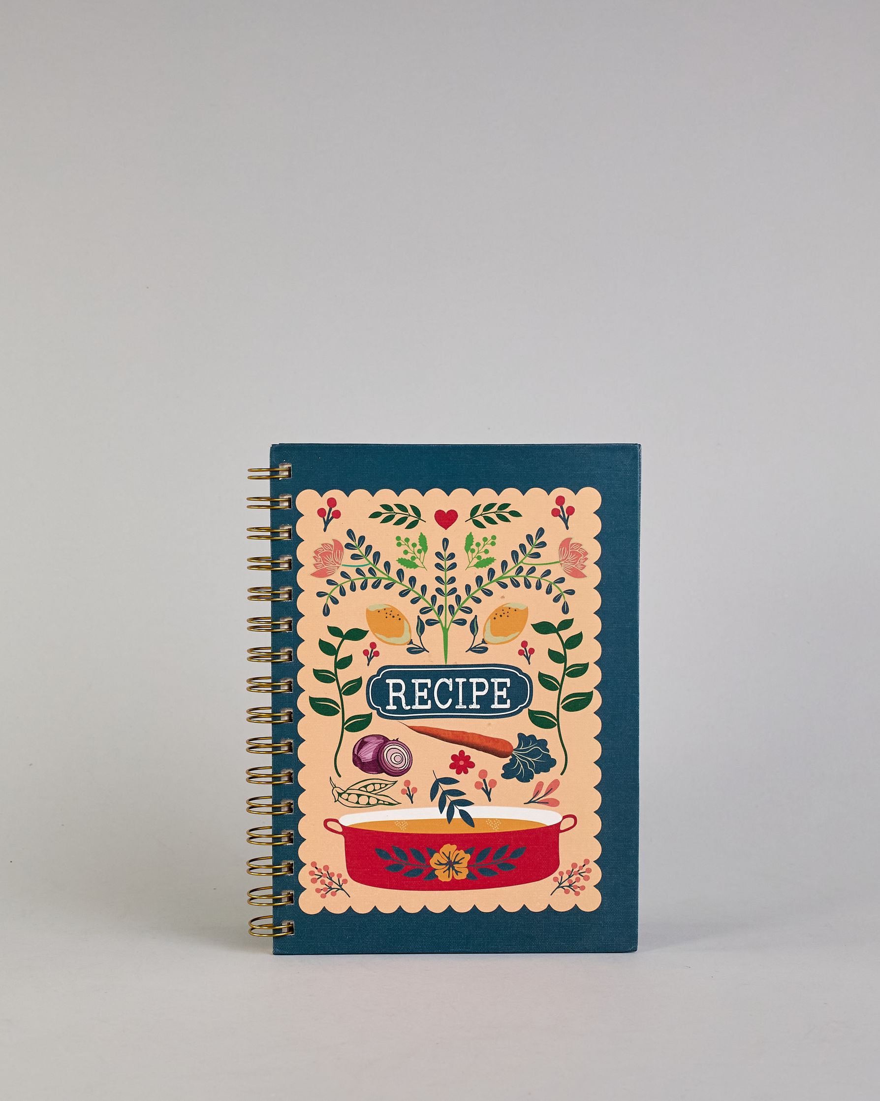 Rezeptbuch mit goldfarbener Spiralbindung und dunkelblauem Einband. Auf der Vorderseite befindet sich ein beigefarbenes Feld mit farbenfrohem, verspieltem Motiv: florale Muster mit Blättern, Blüten, roten Herzen, zwei gelben Vögeln sowie kleinen Illustrationen von Gemüse wie Zwiebel, Karotte und Kohl. Unten ist ein roter Kochtopf mit Blumenornamenten abgebildet. In der Mitte steht das Wort ‚RECIPE‘ in einem dunkelblauen Oval. Auf den cremeweißen Innenseiten sind vorgedruckte Linien und Felder für das Eintr…
