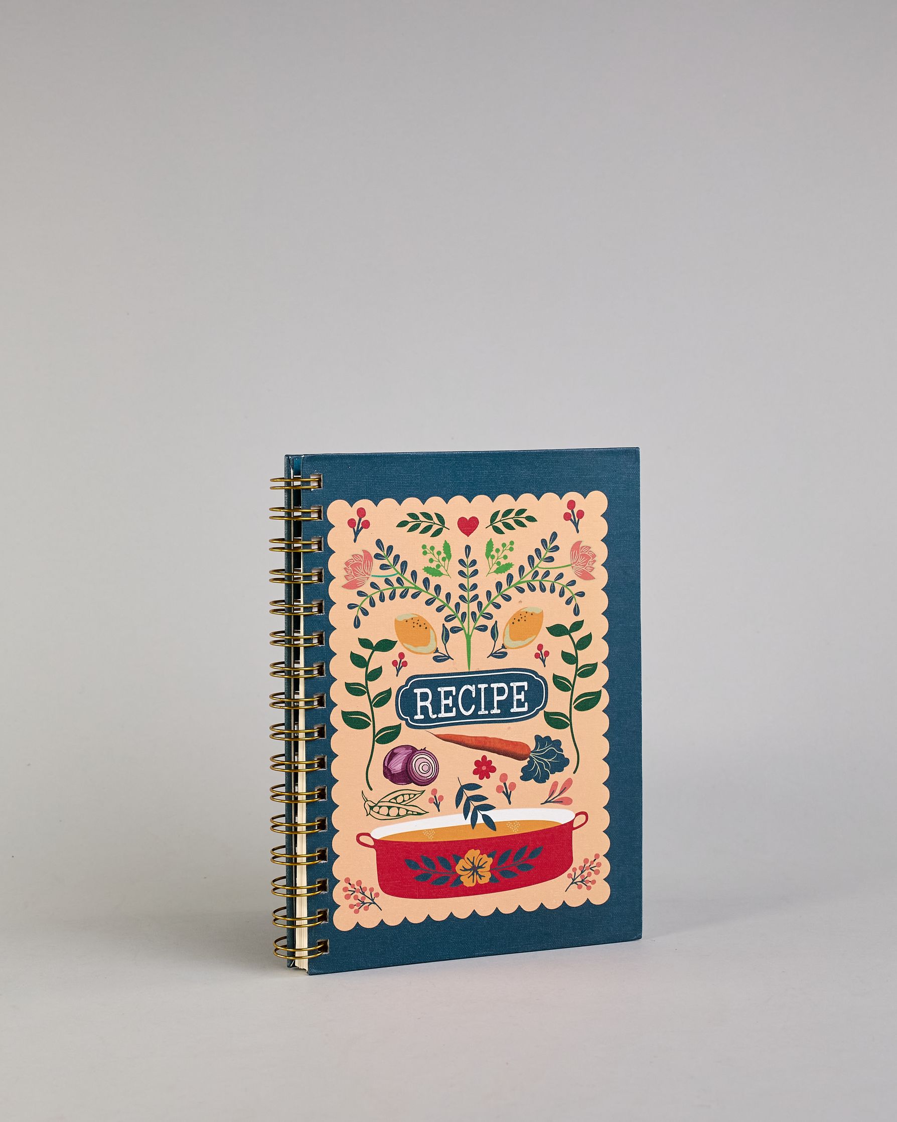 Rezeptbuch mit goldfarbener Spiralbindung und dunkelblauem Einband. Auf der Vorderseite befindet sich ein beigefarbenes Feld mit farbenfrohem, verspieltem Motiv: florale Muster mit Blättern, Blüten, roten Herzen, zwei gelben Vögeln sowie kleinen Illustrationen von Gemüse wie Zwiebel, Karotte und Kohl. Unten ist ein roter Kochtopf mit Blumenornamenten abgebildet. In der Mitte steht das Wort ‚RECIPE‘ in einem dunkelblauen Oval. Auf den cremeweißen Innenseiten sind vorgedruckte Linien und Felder für das Eintr…