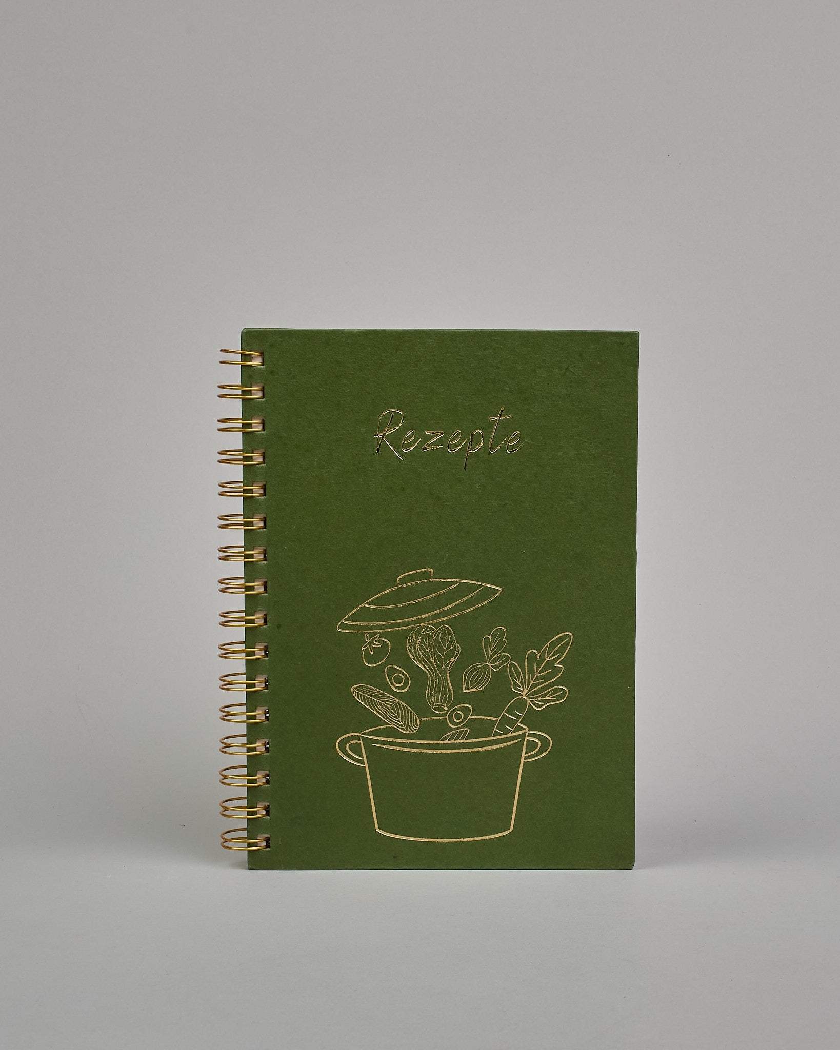 Spiral-Kochbuch mit goldender Spiralbindung, das Cover ist grün und hat eine goldene Prägung die einen Kochtopf darstellt mit Gemüse, drüber steht ebenso in gold Rezepte #1