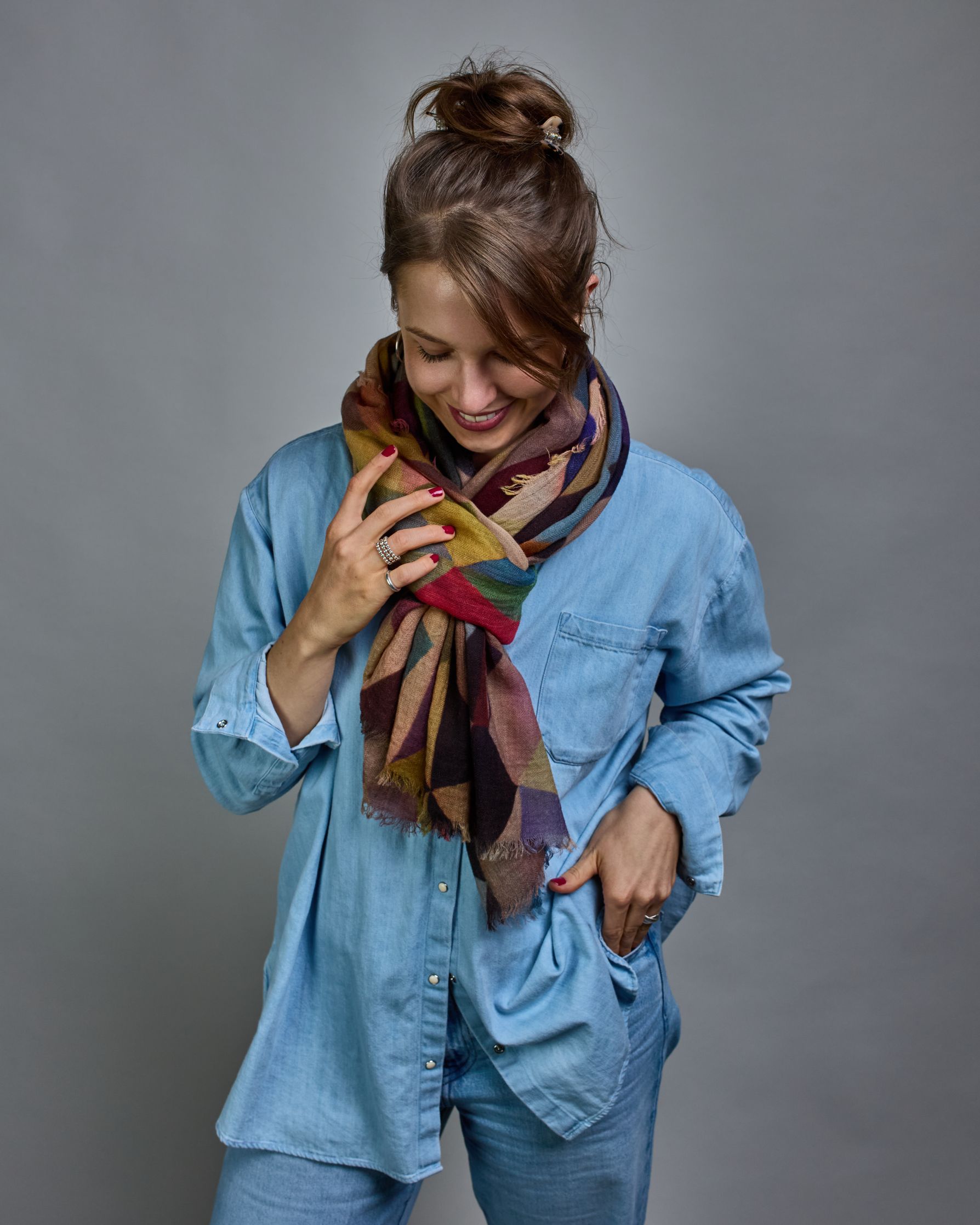 Ein Schal aus 75 % Wolle und 25 % Modal mit den Maßen 100 × 180 cm. Je nach Bild ist er locker um den Nacken gelegt oder einmal gewickelt, um eine lockere Schlaufe um den Hals zu haben, oder zweimal gewickelt, um das Maximum an Wärme zu bekommen. An den Kanten ist er leicht gefranst. Über den ganzen Schal ist ein symetrisches Dreieckmuster verteilt. Die Dreiecke sind in Grau-, Rot-, Blau- Rosa-, Lila-, Grün- und Brauntönen gehalten. #6