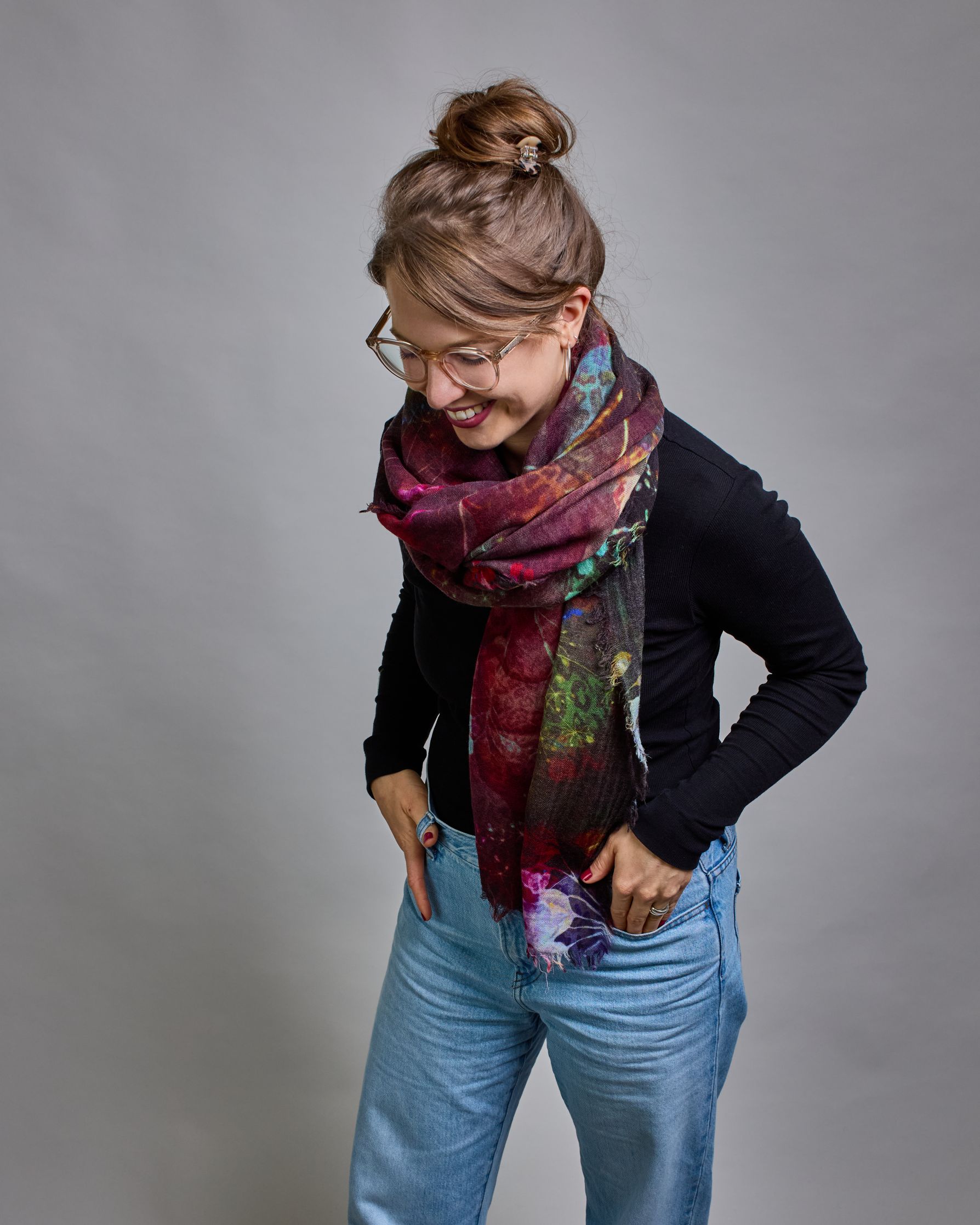 Ein Schal aus 75 % Wolle und 25 % Modal mit den Maßen 100 × 180 cm. Je nach Bild ist er locker um den Nacken gelegt oder einmal gewickelt, um eine lockere Schlaufe um den Hals zu haben, oder zweimal gewickelt, um das Maximum an Wärme zu bekommen. An den Kanten ist er leicht gefranst. Die Hintergrundfarbe des Schals ist Schwarz während sich filigrane Pusteblumen und Blätter in leuchtenden Türkis-, Rot-, Gelb- und Rosatönen verteilen. #3