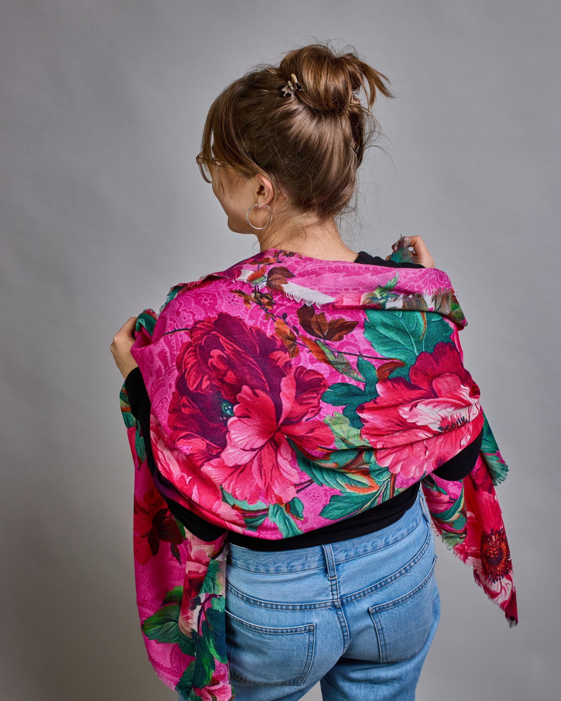 Ein Schal aus 75 % Wolle und 25 % Modal mit den Maßen 70 × 180 cm. Je nach Bild ist er locker um den Nacken gelegt oder einmal gewickelt, um eine lockere Schlaufe um den Hals zu haben, oder zweimal gewickelt, um das Maximum an Wärme zu bekommen. An den Kanten ist er leicht gefranst. Die Hintergrundfarbe des Schals ist pink. Auf dem ganzen Schal sind Blumen in Rot-, und Pinktönen sowie Blätter beziehungsweise Blumenstängel in verschiedenen Grüntönen verteilt. #5