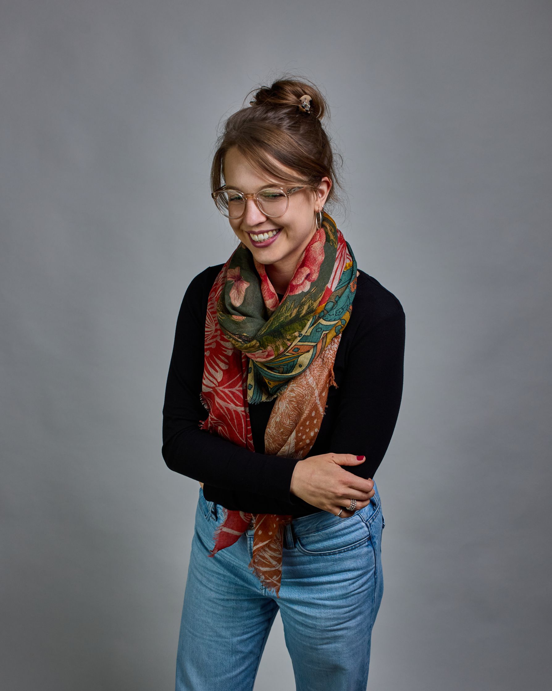 Ein Schal aus 90 % Wolle und 10% Seide. Je nach Bild ist er locker um den Nacken gelegt oder einmal gewickelt, um eine lockere Schlaufe um den Hals zu haben, oder zweimal gewickelt, um das Maximum an Wärme zu bekommen. An den Kanten ist er leicht gefranst. Das Design ist in 4 gleichgroße Quadrate aufgeteilt die jeweils ein anderes Muster hat. Die Quadrate sind mit einem aufgenähtem Okkerfarbenen Samtband unterteilt. Eines der Quadrate hat als Grundfarbe Petrol und darauf befinden sich in verschiedenen Rosa…