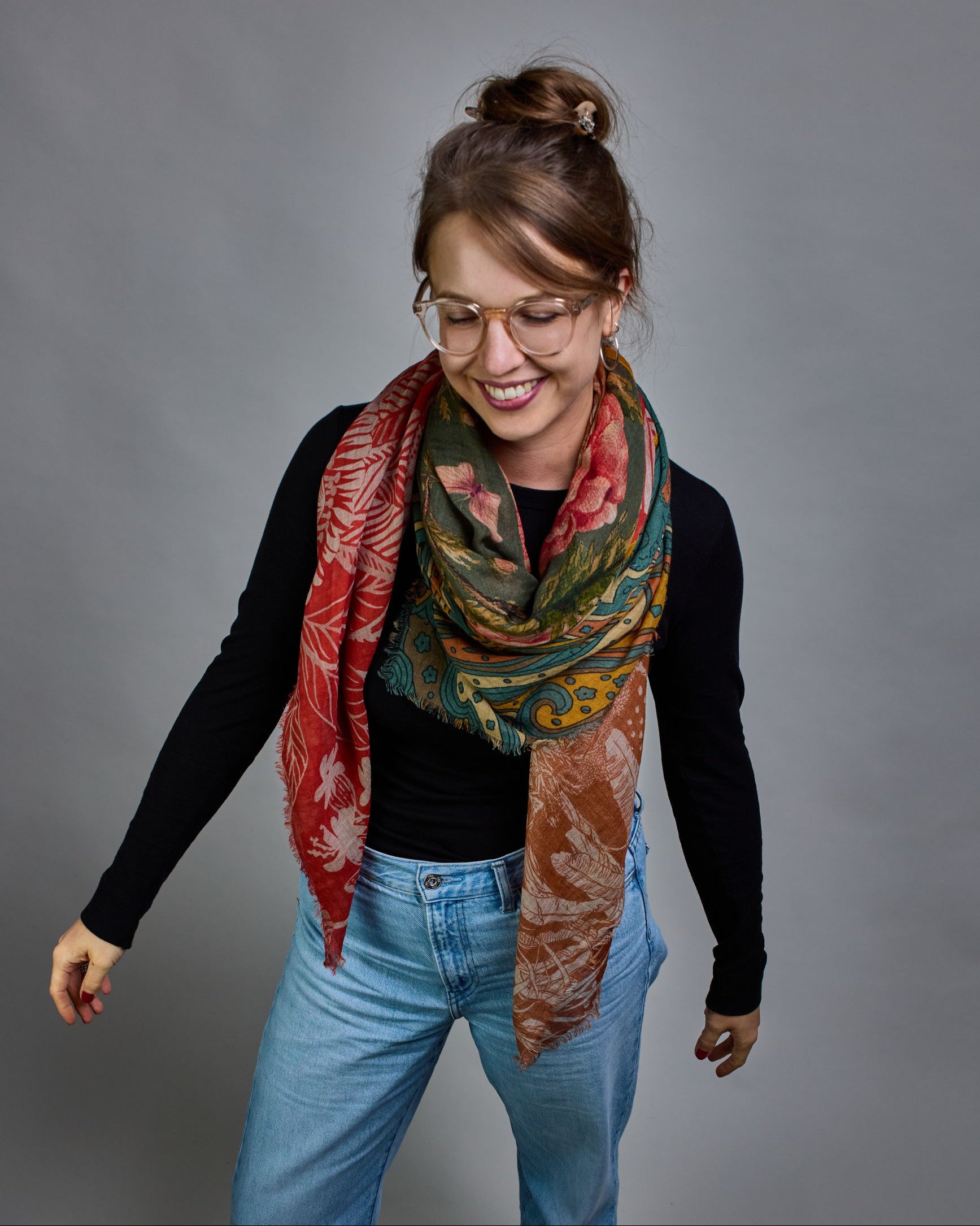 Ein Schal aus 90 % Wolle und 10% Seide. Je nach Bild ist er locker um den Nacken gelegt oder einmal gewickelt, um eine lockere Schlaufe um den Hals zu haben, oder zweimal gewickelt, um das Maximum an Wärme zu bekommen. An den Kanten ist er leicht gefranst. Das Design ist in 4 gleichgroße Quadrate aufgeteilt die jeweils ein anderes Muster hat. Die Quadrate sind mit einem aufgenähtem Okkerfarbenen Samtband unterteilt. Eines der Quadrate hat als Grundfarbe Petrol und darauf befinden sich in verschiedenen Rosa…