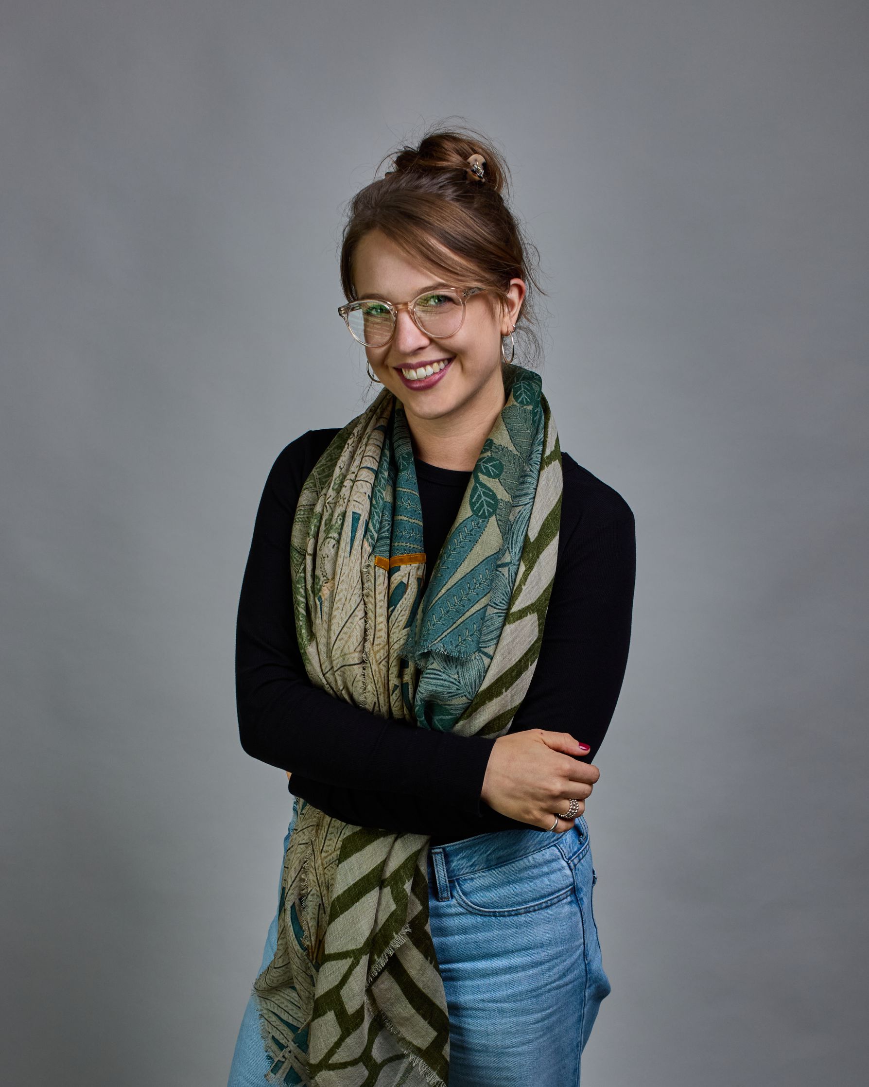 Ein Schal aus 90 % Wolle und 10% Seide. Je nach Bild ist er locker um den Nacken gelegt oder einmal gewickelt, um eine lockere Schlaufe um den Hals zu haben, oder zweimal gewickelt, um das Maximum an Wärme zu bekommen. An den Kanten ist er leicht gefranst. Das Design ist in 4 gleichgroße Quadrate aufgeteilt die jeweils ein anderes Muster hat. Die Quadrate sind mit einem aufgenähtem Okkerfarbenen Samtband unterteilt. Eines der Quadrate hat als Grundfarbe Cremeweiß und darauf befinden sich in verschiedenen G…