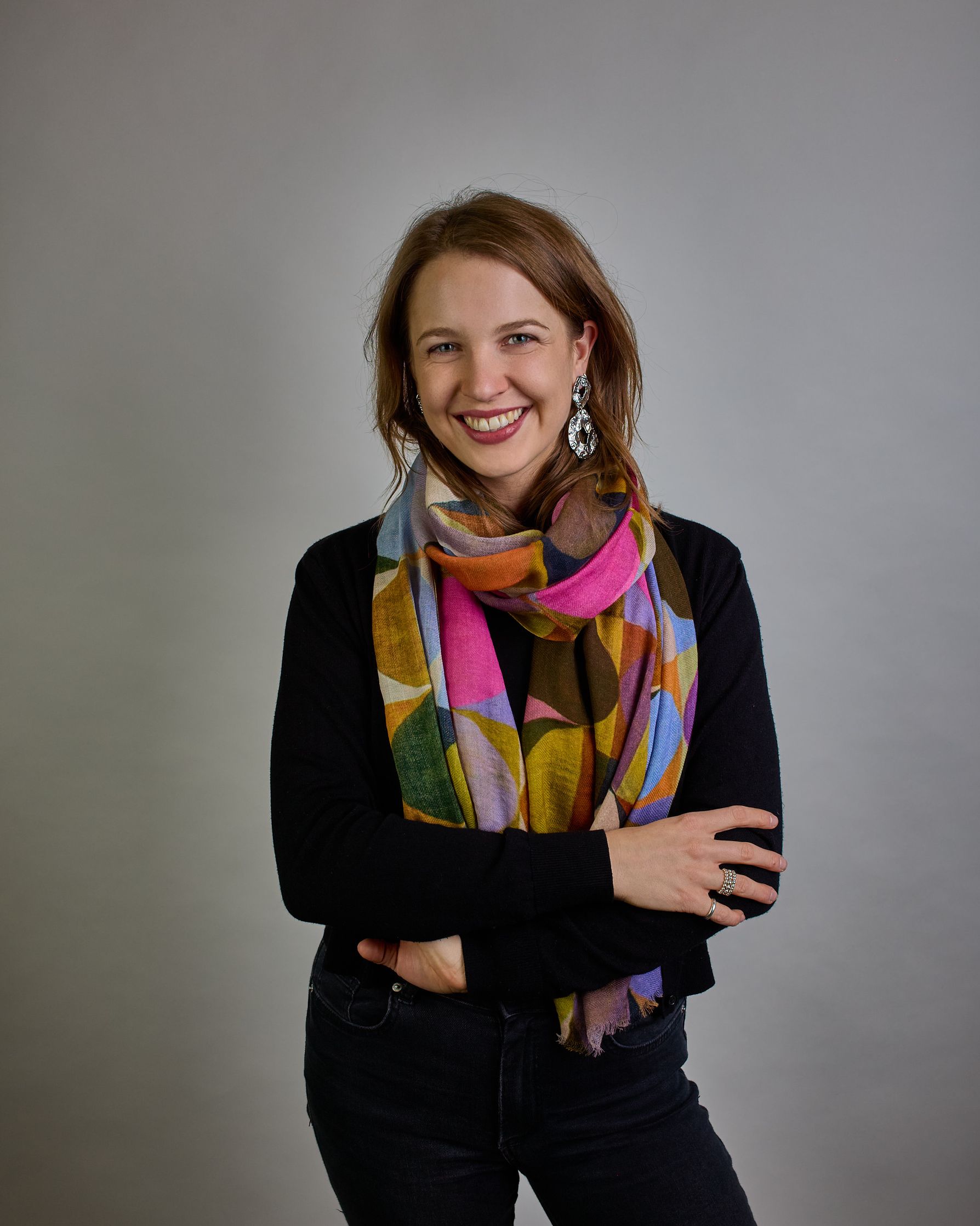 Ein Schal aus 75 % Wolle und 25 % Modal mit den Maßen 100 × 180 cm. Je nach Bild ist er locker um den Nacken gelegt oder einmal gewickelt, um eine lockere Schlaufe um den Hals zu haben, oder zweimal gewickelt, um das Maximum an Wärme zu bekommen. An den Kanten ist er leicht gefranst. Über den ganzen Schal ist ein symetrisches Kreismuster verteilt. Die Dreiecke sind in Grau-, Rot-, Blau- Rosa-, Lila-, Grün- und Brauntönen gehalten. #2