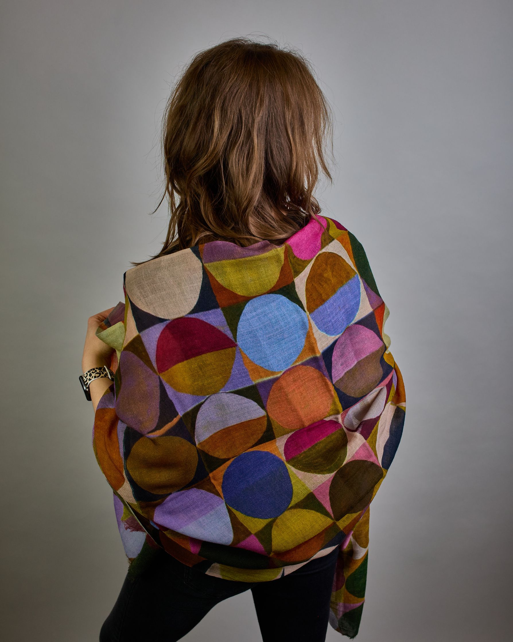 Ein Schal aus 75 % Wolle und 25 % Modal mit den Maßen 100 × 180 cm. Je nach Bild ist er locker um den Nacken gelegt oder einmal gewickelt, um eine lockere Schlaufe um den Hals zu haben, oder zweimal gewickelt, um das Maximum an Wärme zu bekommen. An den Kanten ist er leicht gefranst. Über den ganzen Schal ist ein symetrisches Kreismuster verteilt. Die Dreiecke sind in Grau-, Rot-, Blau- Rosa-, Lila-, Grün- und Brauntönen gehalten. #4