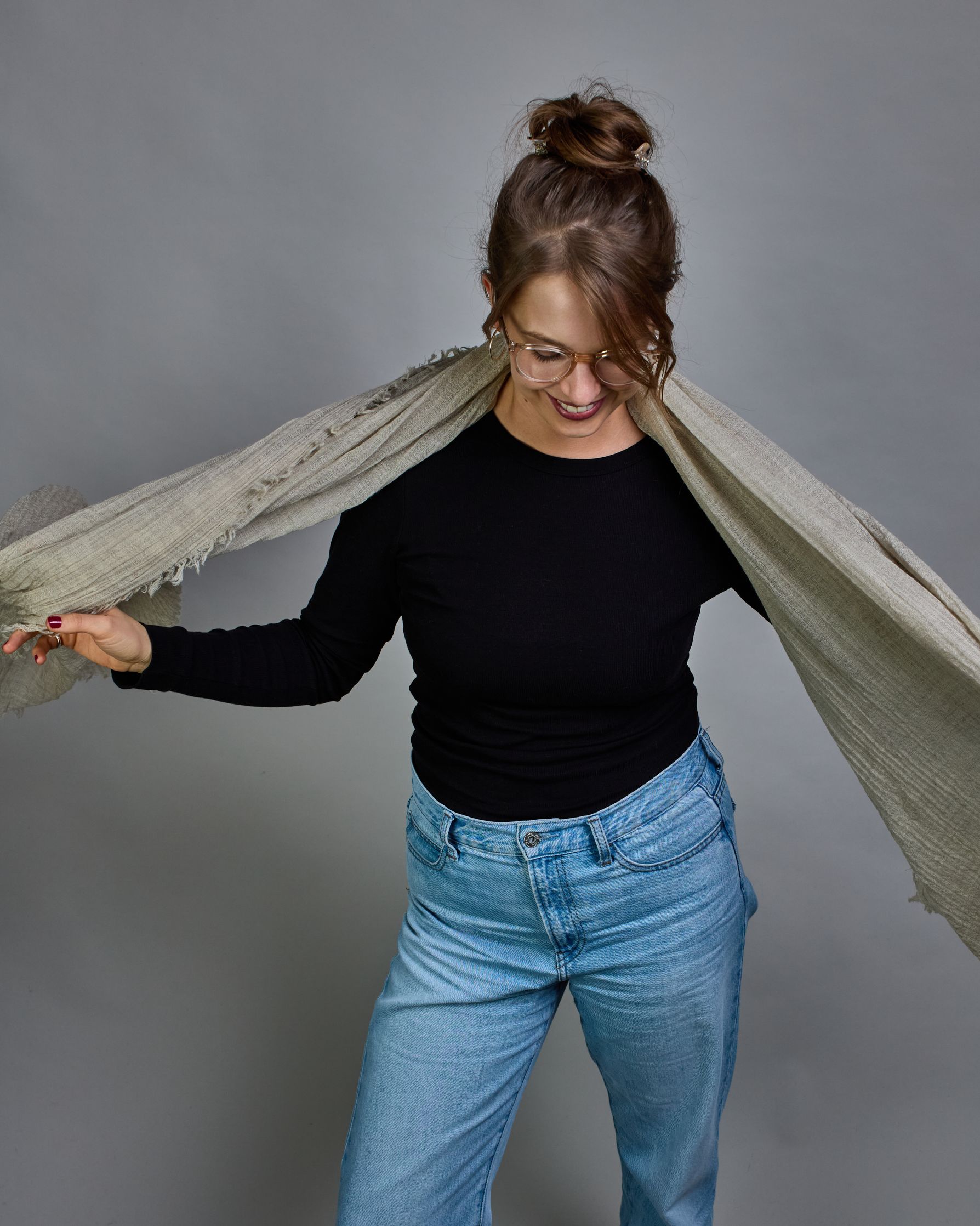 Ein beiger Schal aus 100 % Wolle mit den Maßen 100x180 cm. Je nach Bild ist er locker um den Hals gelegt oder einmal gewickelt, um eine Schlaufe um den Hals zu haben. Der Schal ist einfärbig und hat an den Kanten leichte Fransen. Die organische Struktur verleiht dem Schal ein lässiges, zeitloses Design. #4