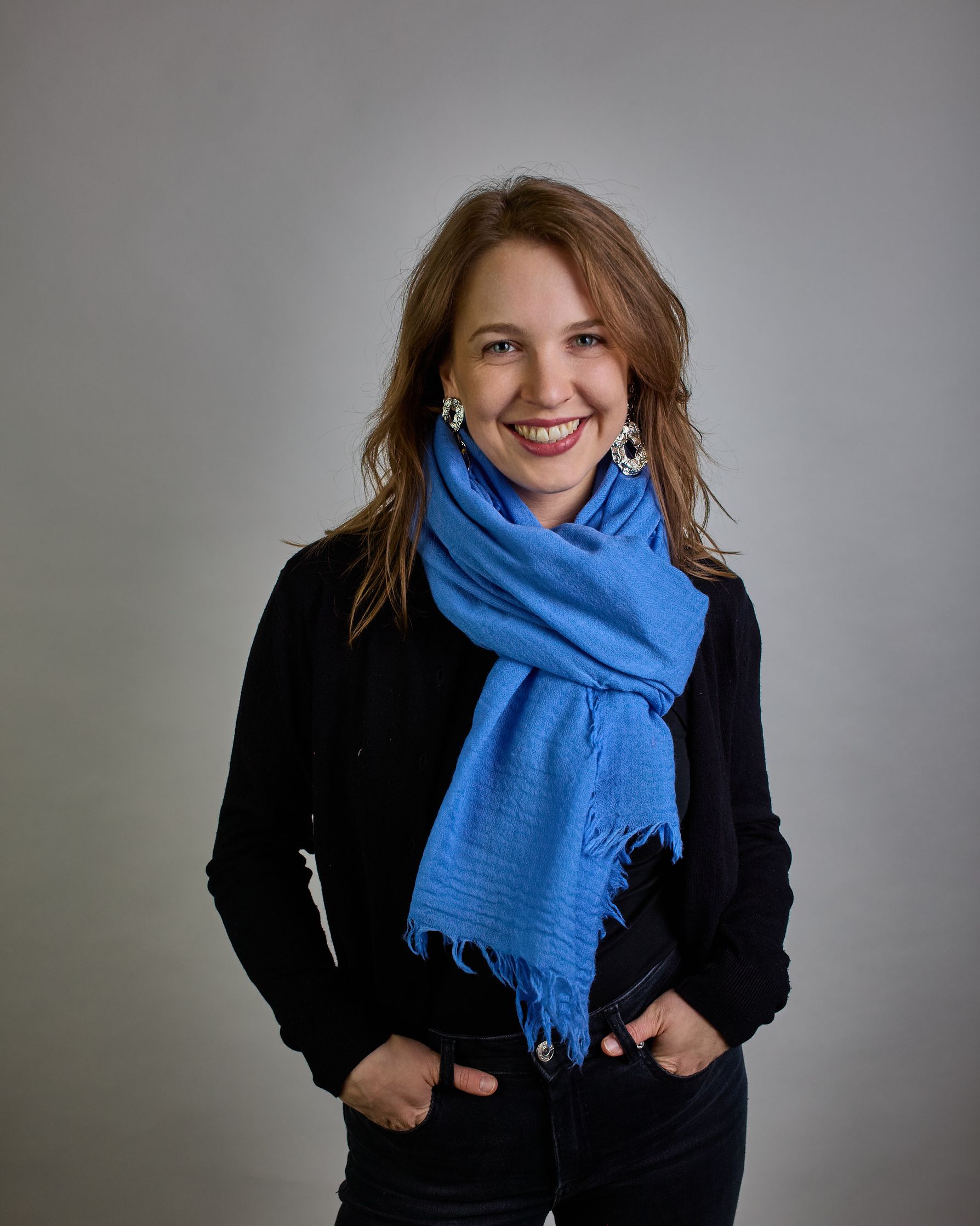 Ein Schal aus 100 % Wolle in einem kaltem Mittel Blauton mit den Maßen 100x180 cm. Je nach Bild ist er locker um den Hals gelegt oder einmal gewickelt, um eine Schlaufe um den Hals zu haben. Der Schal ist einfärbig und hat an den Kanten leichte Fransen. Die organische Struktur verleiht dem Schal ein lässiges, zeitloses Design. #2