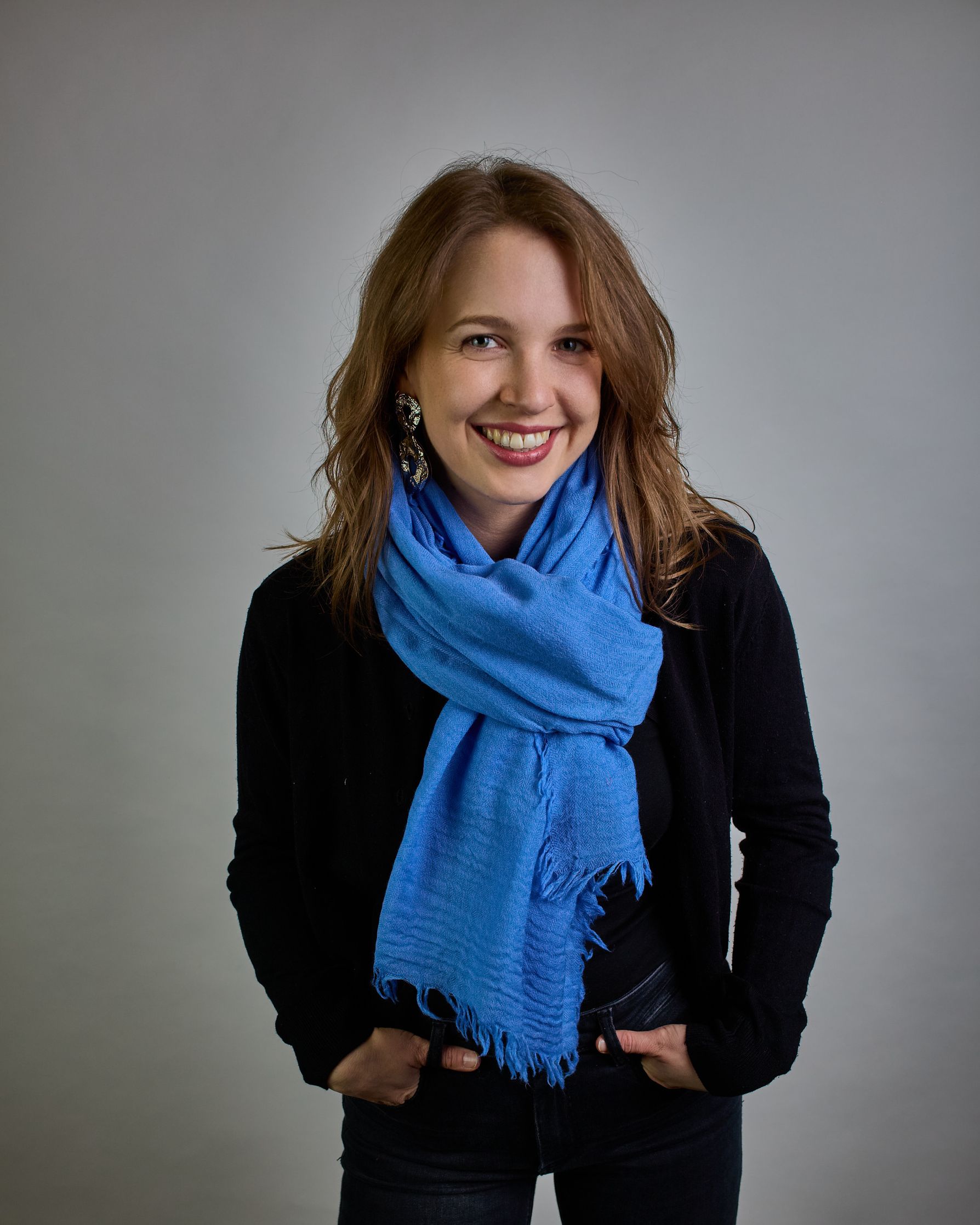 Ein Schal aus 100 % Wolle in einem kaltem Mittel Blauton mit den Maßen 100x180 cm. Je nach Bild ist er locker um den Hals gelegt oder einmal gewickelt, um eine Schlaufe um den Hals zu haben. Der Schal ist einfärbig und hat an den Kanten leichte Fransen. Die organische Struktur verleiht dem Schal ein lässiges, zeitloses Design. #3