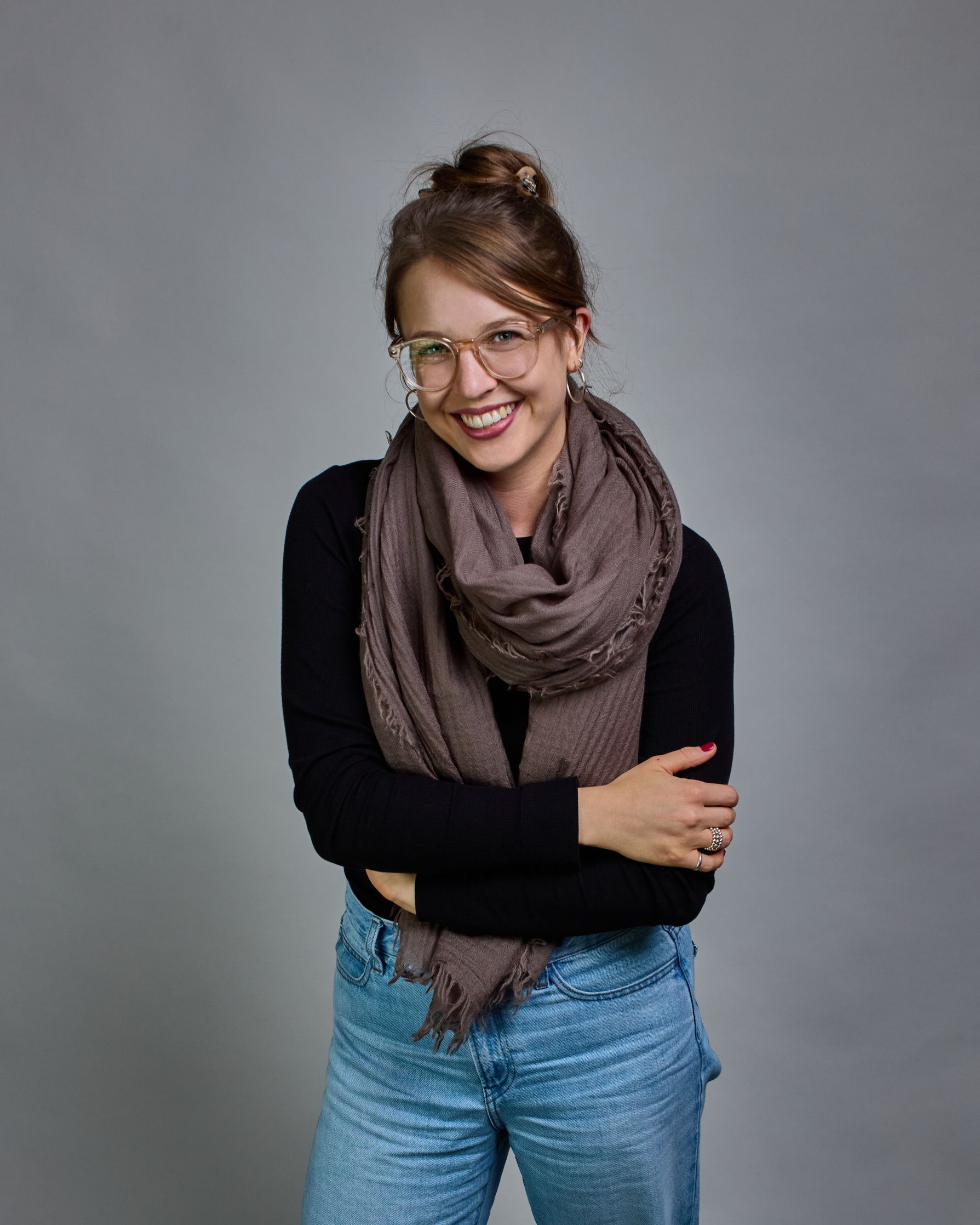 Ein Schal aus 100 % Wolle in einem kaltem Braunton mit den Maßen 100x180 cm. Je nach Bild ist er locker um den Hals gelegt oder einmal gewickelt, um eine Schlaufe um den Hals zu haben. Der Schal ist einfärbig und hat an den Kanten leichte Fransen. Die organische Struktur verleiht dem Schal ein lässiges, zeitloses Design. #1