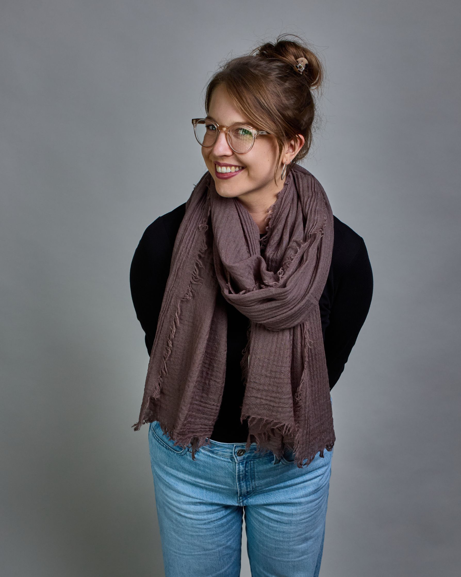 Ein Schal aus 100 % Wolle in einem warmen Braunton mit den Maßen 100x180 cm. Je nach Bild ist er locker um den Hals gelegt oder einmal gewickelt, um eine Schlaufe um den Hals zu haben. Der Schal ist einfärbig und hat an den Kanten leichte Fransen. Die organische Struktur verleiht dem Schal ein lässiges, zeitloses Design. #1