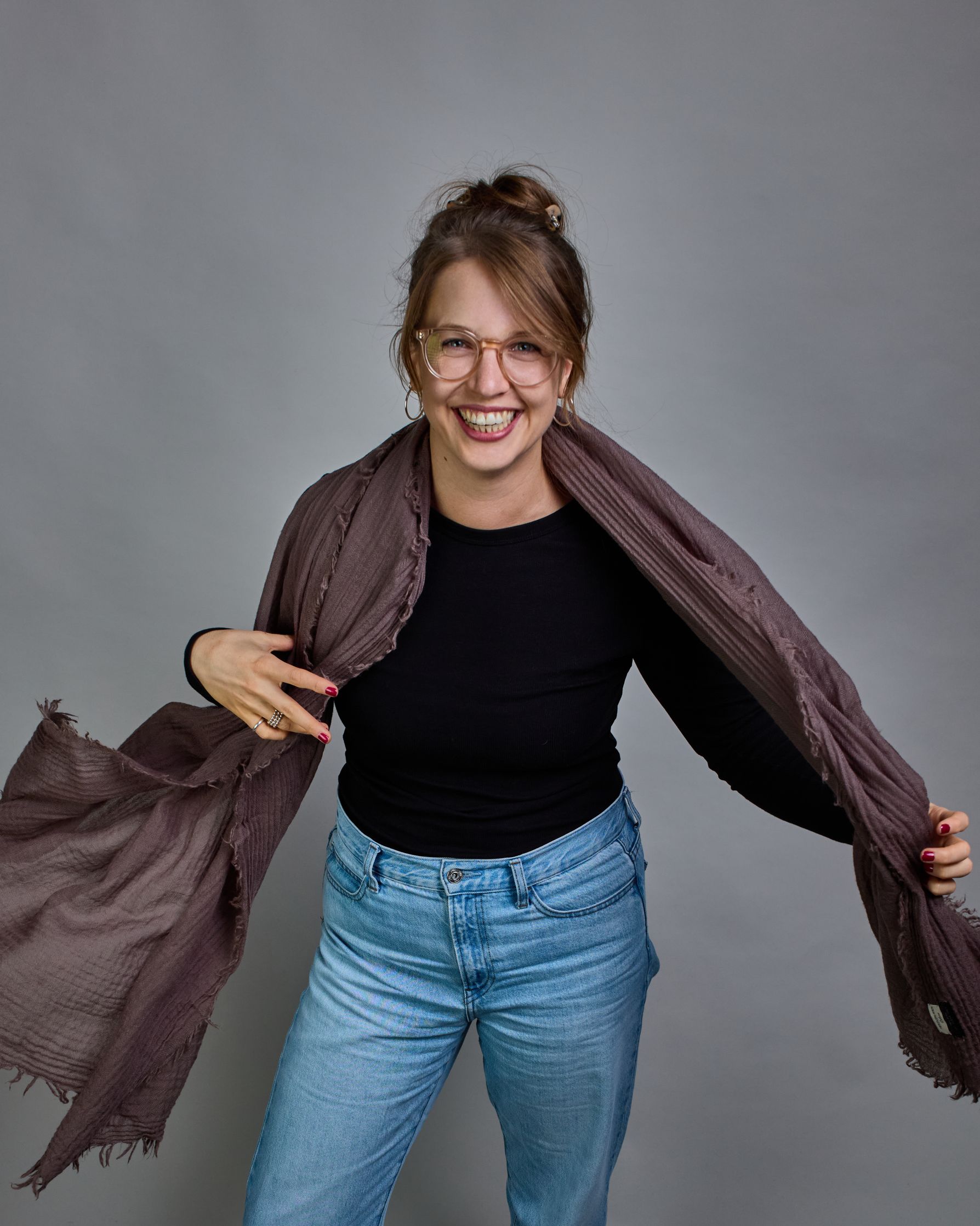 Ein Schal aus 100 % Wolle in einem warmen Braunton mit den Maßen 100x180 cm. Je nach Bild ist er locker um den Hals gelegt oder einmal gewickelt, um eine Schlaufe um den Hals zu haben. Der Schal ist einfärbig und hat an den Kanten leichte Fransen. Die organische Struktur verleiht dem Schal ein lässiges, zeitloses Design. #4