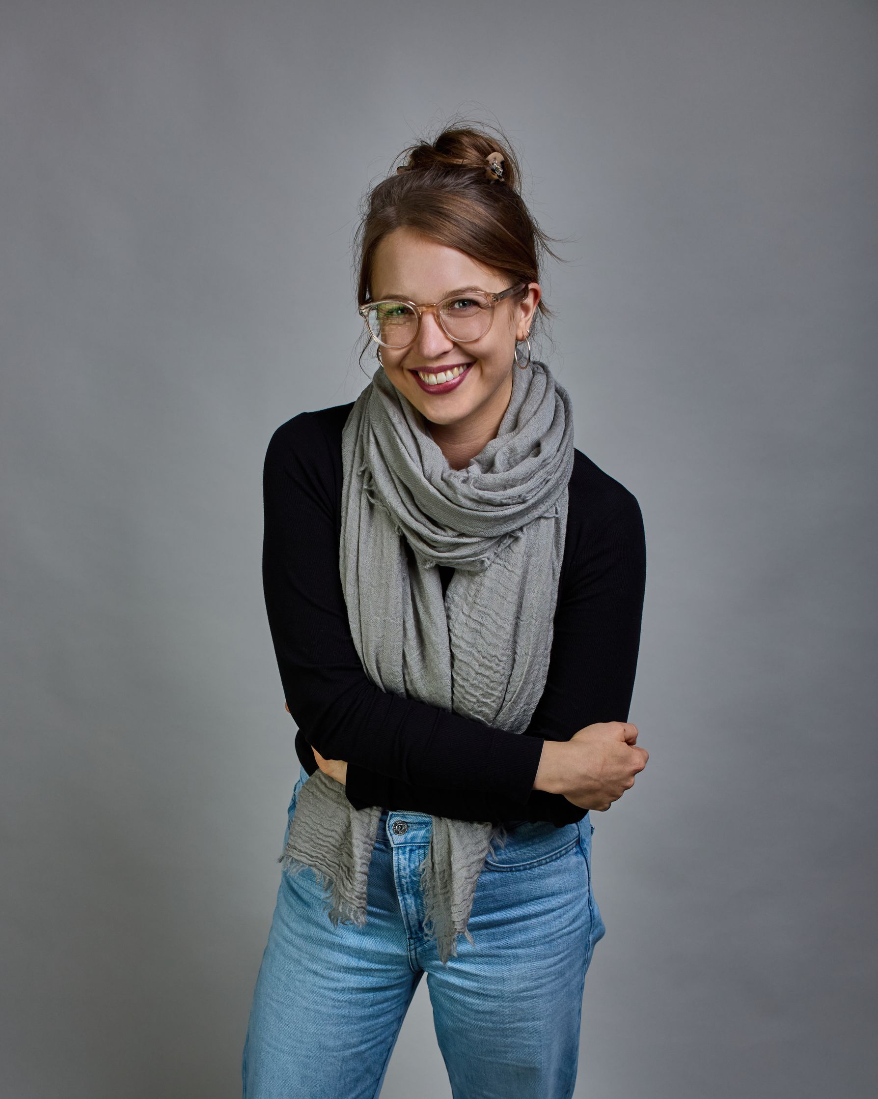 Ein hellgrauer Schal aus 100 % Wolle mit den Maßen 100x180 cm. Je nach Bild ist er locker um den Hals gelegt oder einmal gewickelt, um eine Schlaufe um den Hals zu haben. Der Schal ist einfärbig und hat an den Kanten leichte Fransen. Die organische Struktur verleiht dem Schal ein lässiges, zeitloses Design. #2