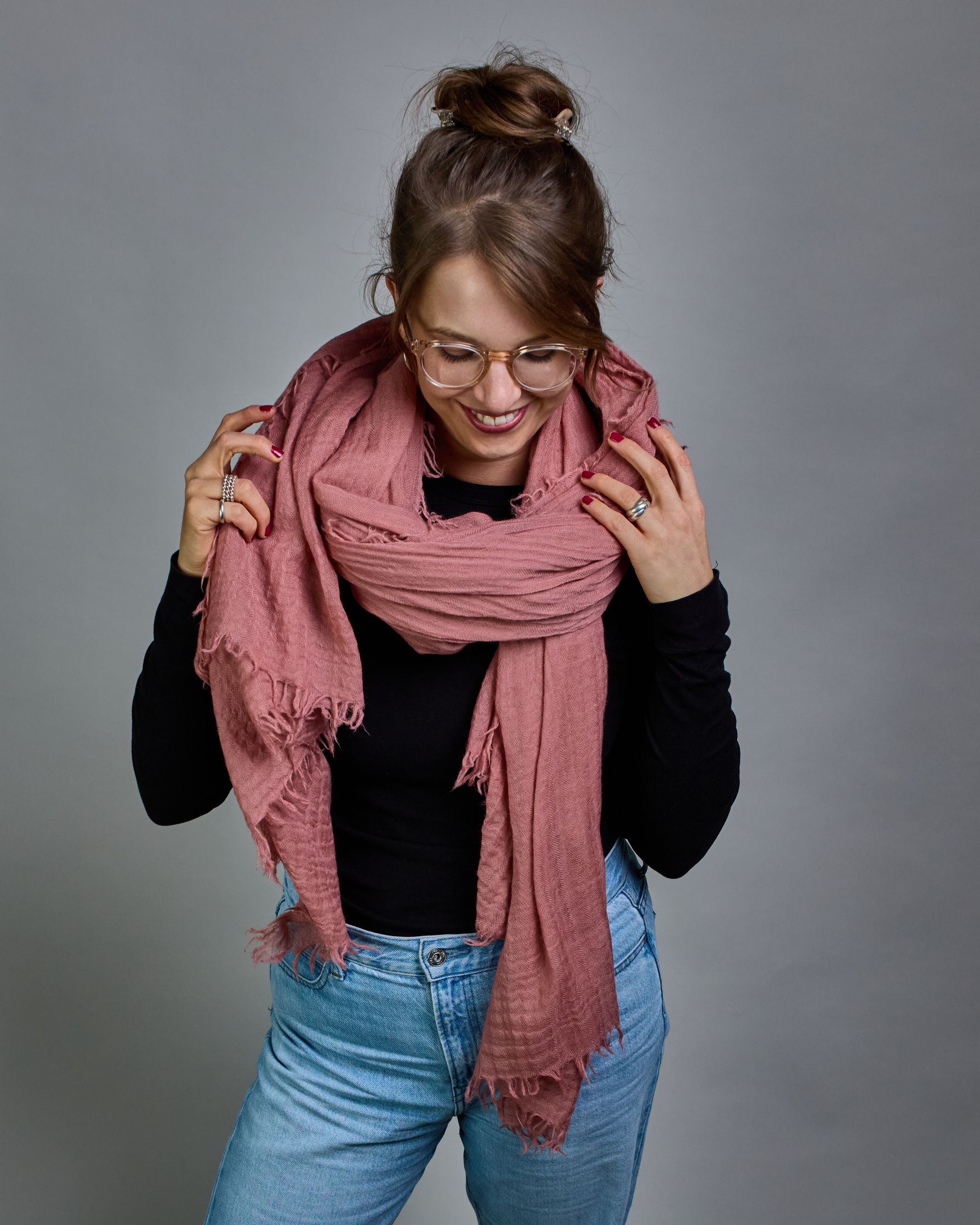 Ein lachsfarbener Schal aus 100 % Wolle mit den Maßen 100x180 cm. Je nach Bild ist er locker um den Hals gelegt oder einmal gewickelt, um eine Schlaufe um den Hals zu haben. Der Schal ist einfärbig und hat an den Kanten leichte Fransen. Die organische Struktur verleiht dem Schal ein lässiges, zeitloses Design. #3