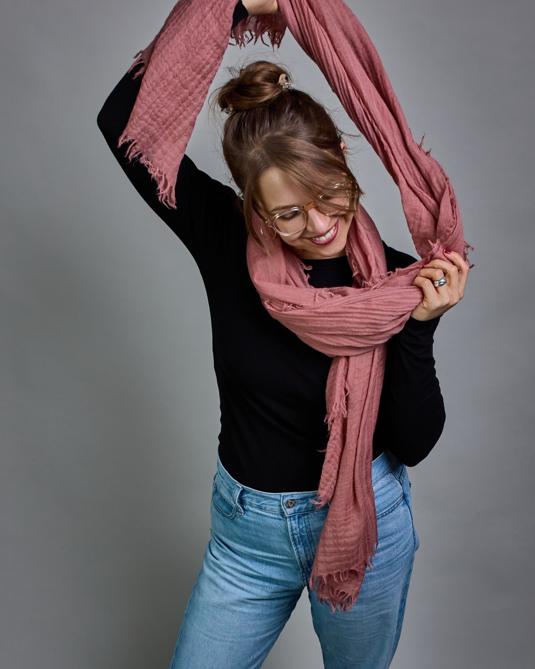 Ein lachsfarbener Schal aus 100 % Wolle mit den Maßen 100x180 cm. Je nach Bild ist er locker um den Hals gelegt oder einmal gewickelt, um eine Schlaufe um den Hals zu haben. Der Schal ist einfärbig und hat an den Kanten leichte Fransen. Die organische Struktur verleiht dem Schal ein lässiges, zeitloses Design. #4