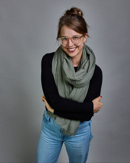 Ein hellgrüner Schal aus 100 % Wolle mit den Maßen 100x180 cm. Je nach Bild ist er locker um den Hals gelegt oder einmal gewickelt, um eine Schlaufe um den Hals zu haben. Der Schal ist einfärbig und hat an den Kanten leichte Fransen. Die organische Struktur verleiht dem Schal ein lässiges, zeitloses Design. #1