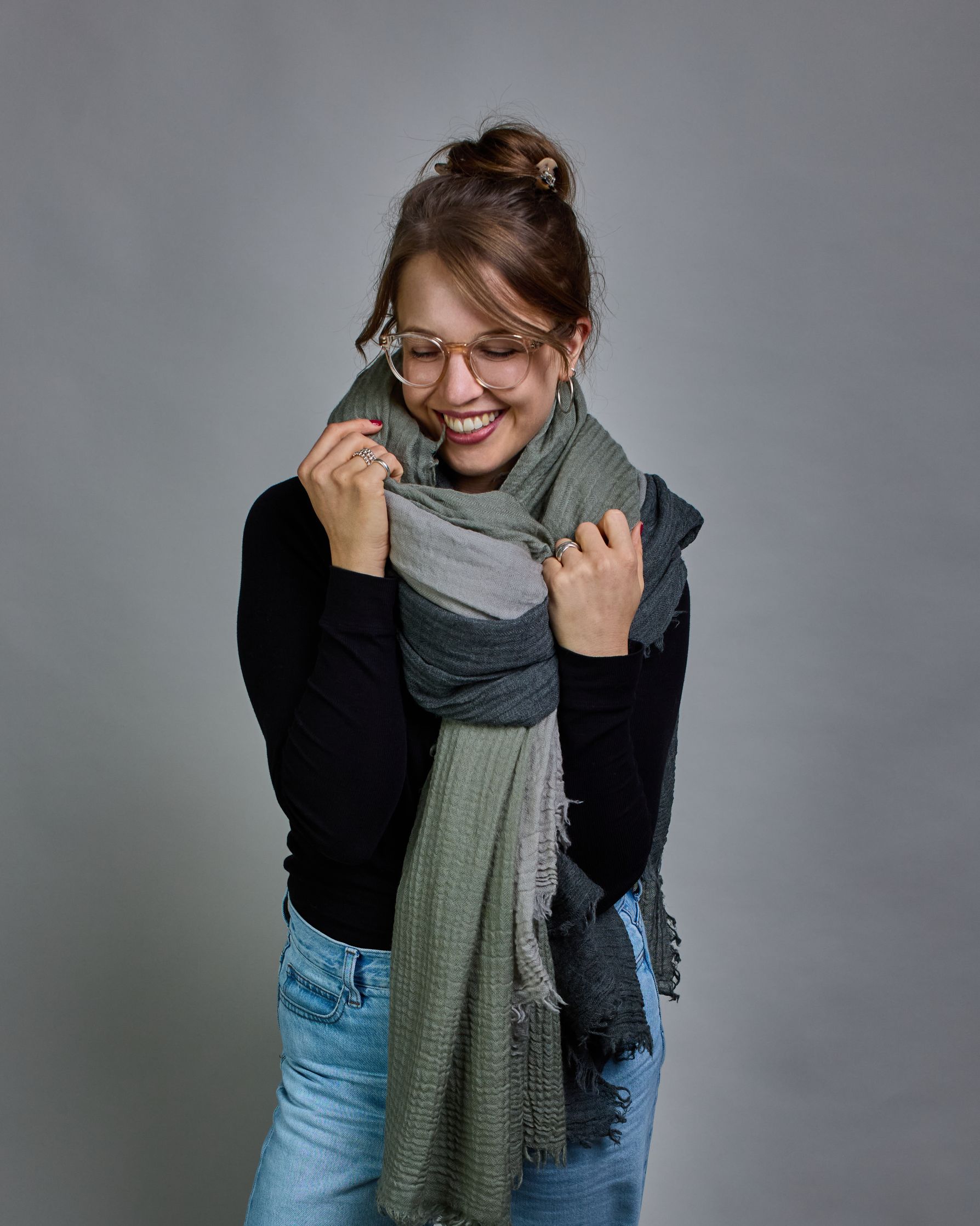 Ein hellgrüner Schal aus 100 % Wolle mit den Maßen 100x180 cm. Je nach Bild ist er locker um den Hals gelegt oder einmal gewickelt, um eine Schlaufe um den Hals zu haben. Der Schal ist einfärbig und hat an den Kanten leichte Fransen. Die organische Struktur verleiht dem Schal ein lässiges, zeitloses Design. #4