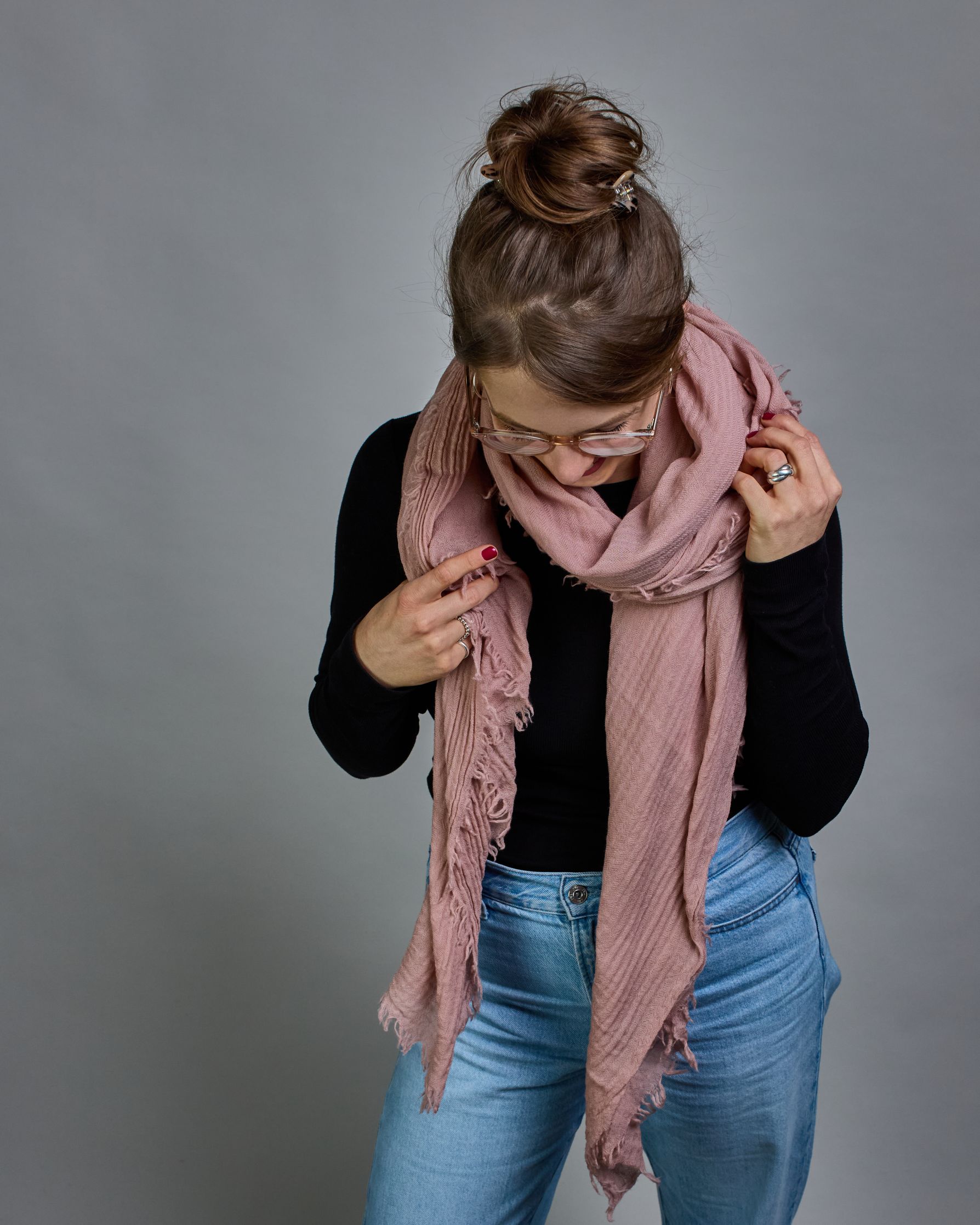 Ein rosafarbener Schal aus 100 % Wolle mit den Maßen 100x180 cm. Je nach Bild ist er locker um den Hals gelegt oder einmal gewickelt, um eine Schlaufe um den Hals zu haben. Der Schal ist einfärbig und hat an den Kanten leichte Fransen. Die organische Struktur verleiht dem Schal ein lässiges, zeitloses Design. #1