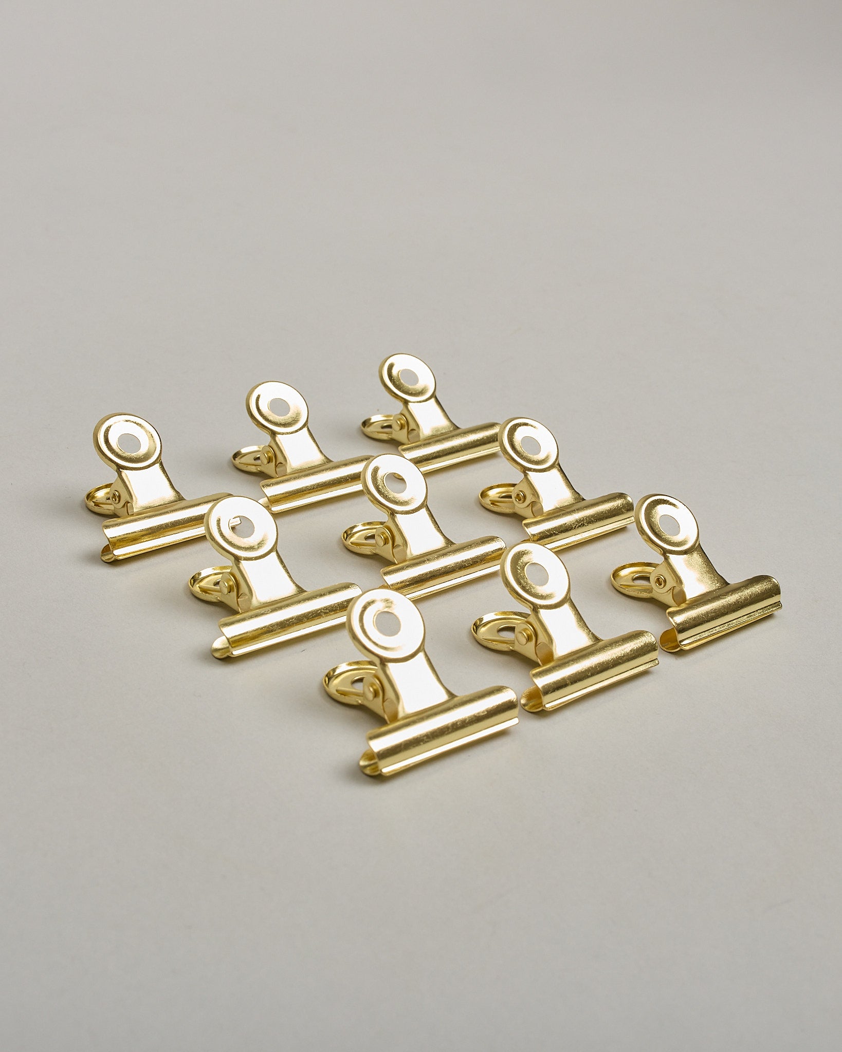 Ein einzelner Metall-Clip in gold mit einem Loch in den Greifarmen an denen man sie oben öffnen kann. #5