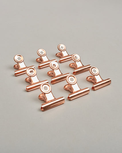 Ein einzelner Metall-Clip in rosé mit einem Loch in den Greifarmen an denen man sie oben öffnen kann. #10