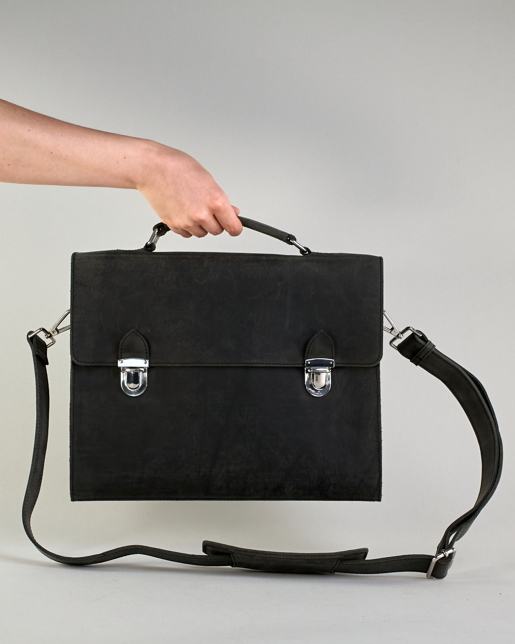 Schwarze Aktentasche aus Hunterleder mit Tragegriff, abnehmbarem Schulterriemen, Metallverschlüssen sowie Innenfächer. Das Lederist anfangs matt und entwickelt mit der Zeit eine individuelle Patina. Logo Prägung unter der Lasche mit zwei Metallverschlüssen in klassischem Schultaschen-Stil. #3